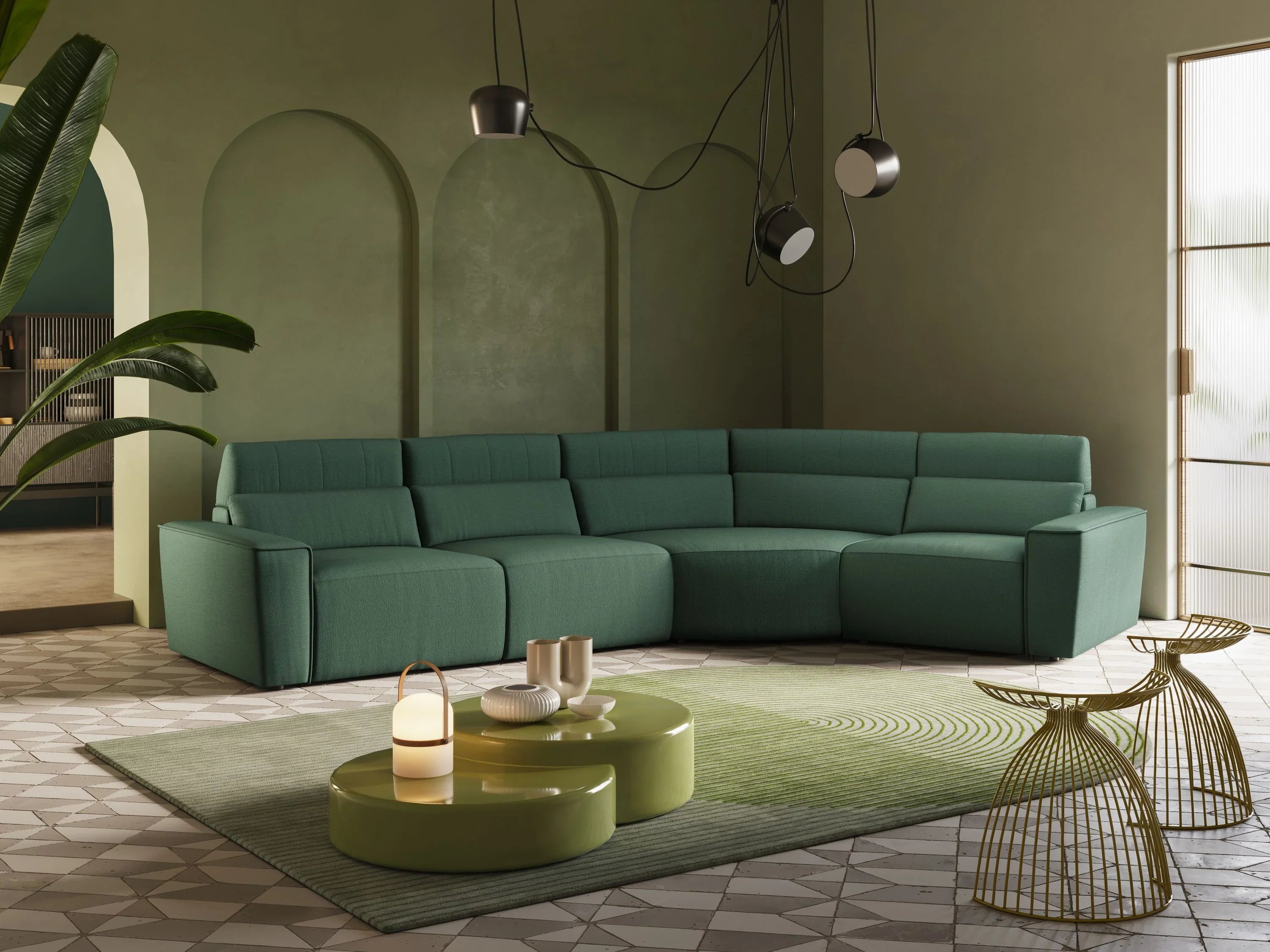 Un moderno divano componibile verde è appoggiato su un tappeto verde con motivi circolari. Due tavolini verdi ospitano oggetti decorativi e nelle vicinanze si trovano sedie con fili dorati. La stanza è caratterizzata da luci soffuse e pareti color oliva.