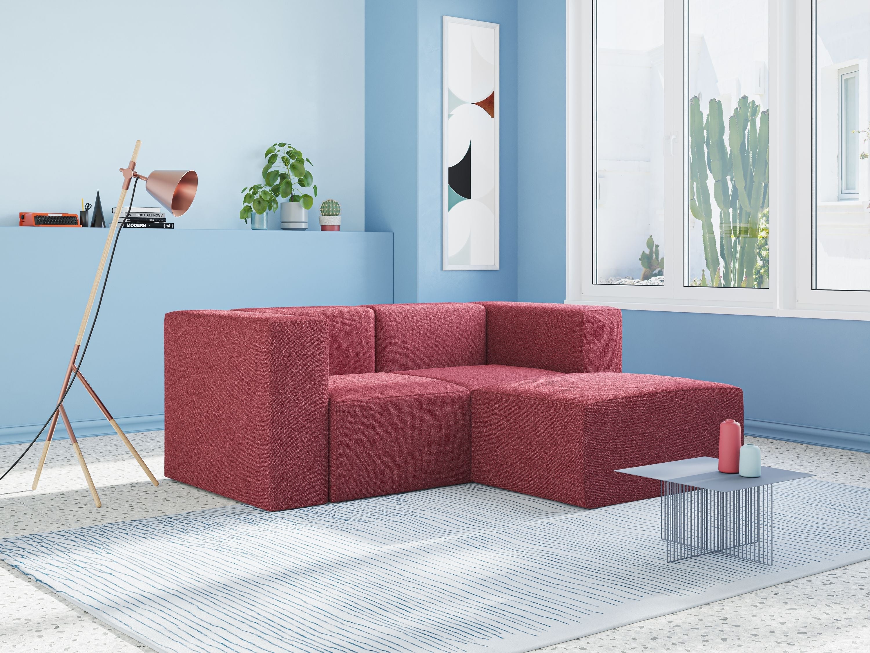 Un soggiorno moderno e minimalista con un divano modulare rosso, pareti blu, una lampada da terra, una pianta in vaso, quadri astratti alle pareti, grandi finestre e un tavolino basso con due vasi su un tappeto a righe.