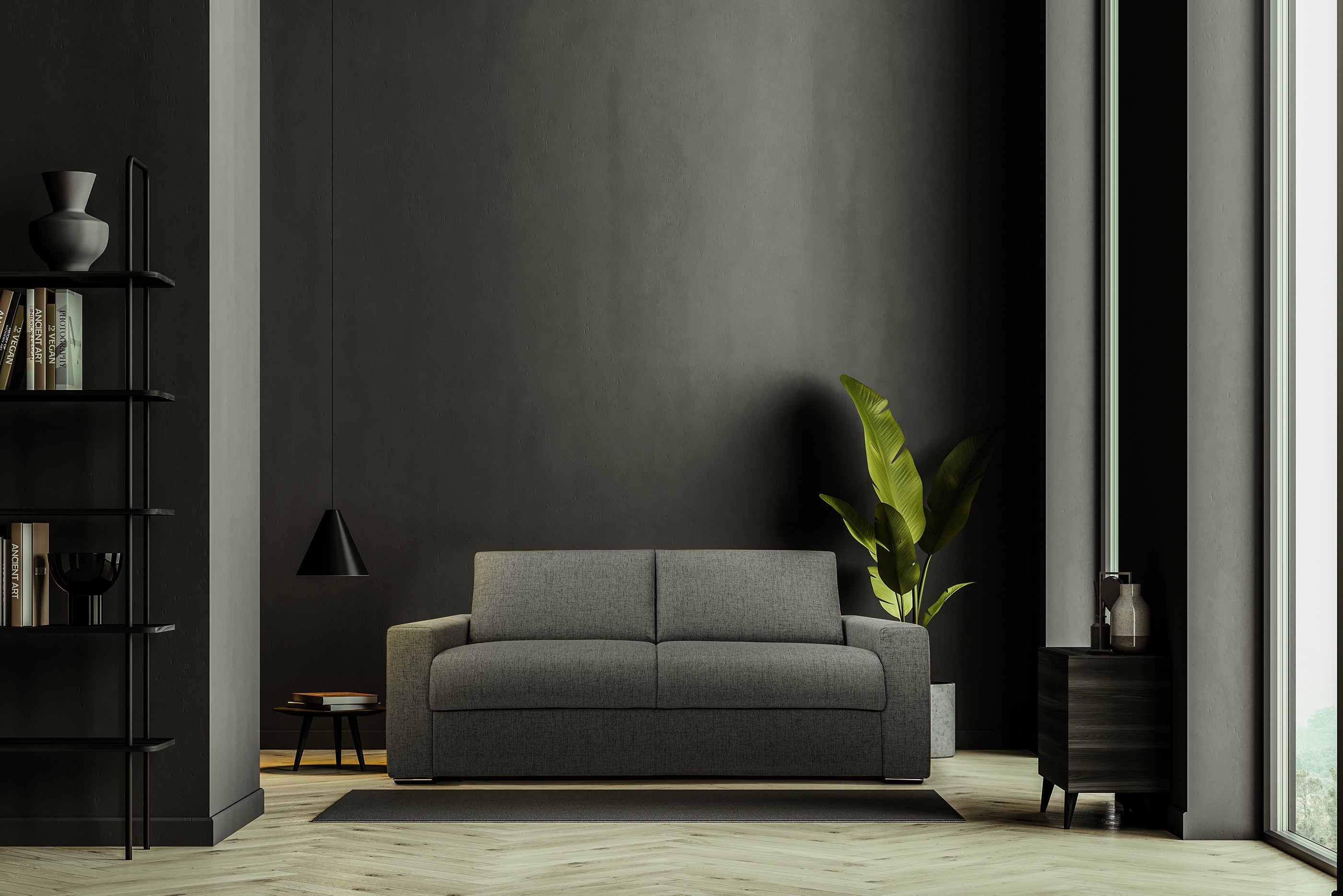Soggiorno minimalista con un divano grigio contro una parete scura, una grande pianta verde in vaso, una lampada a sospensione nera, un tavolino laterale, librerie e luce naturale che entra da destra.