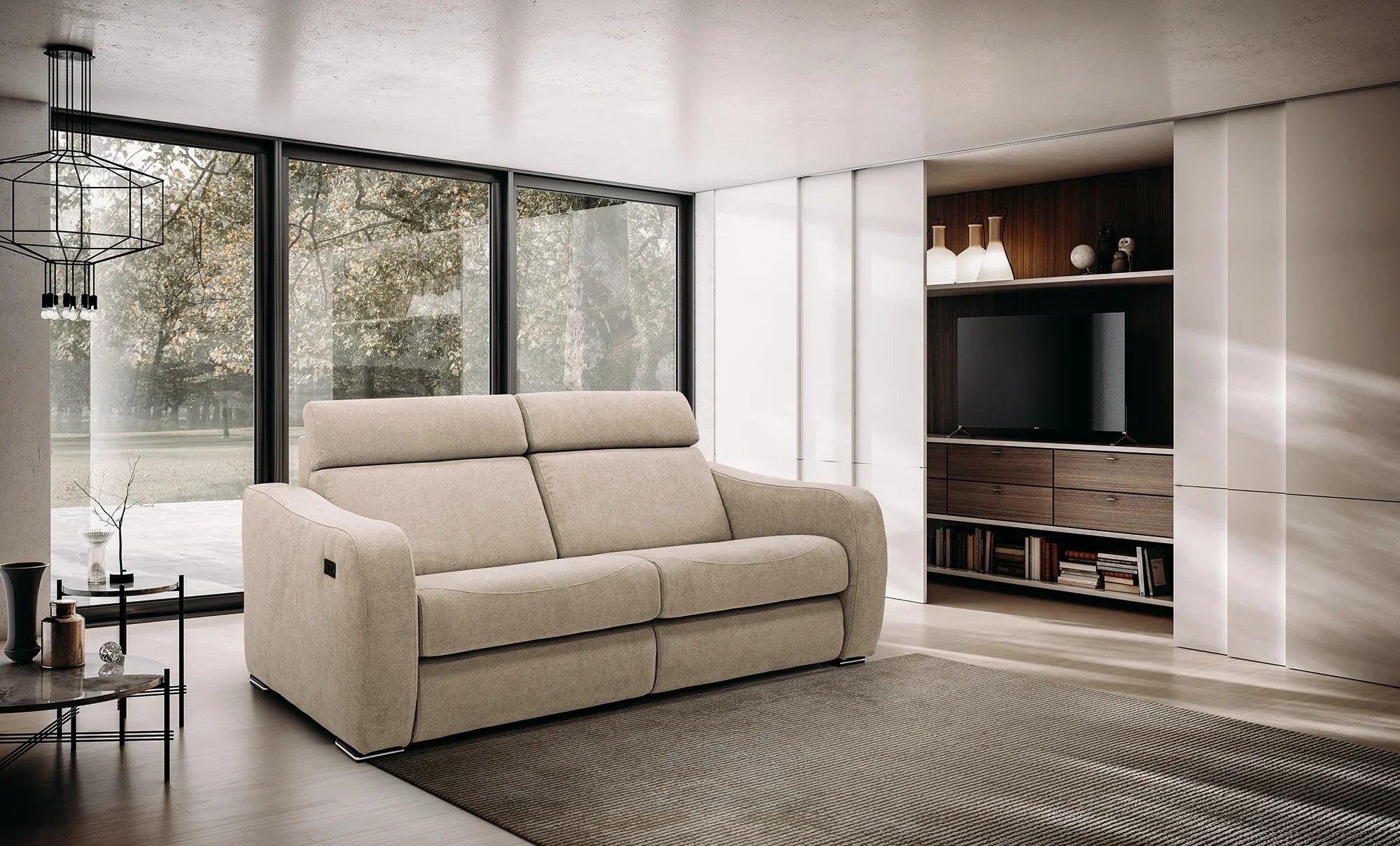 Soggiorno moderno con un grande divano beige disposto al centro su un tappeto neutro, finestre a tutta altezza con alberi e un mobile per l'intrattenimento integrato con TV, libri e vasi decorativi.