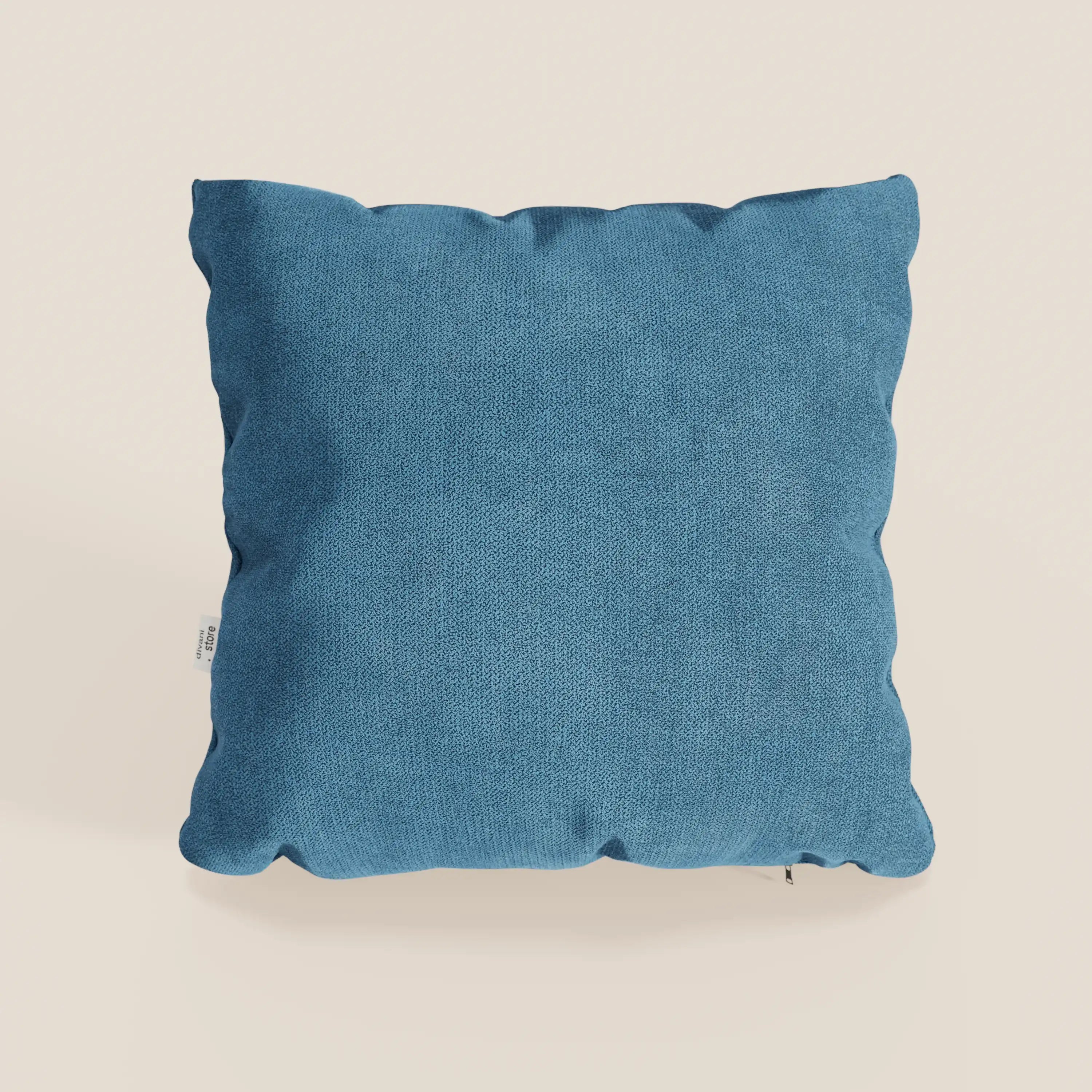 Il cuscino Destiny 45x45 cm di Divani.Store, in T02 azzurro tessuto morbido impermeabile, è caratterizzato da un tessuto blu morbido e strutturato con cuciture a vista e una piccola etichetta bianca, su uno sfondo bianco sporco.