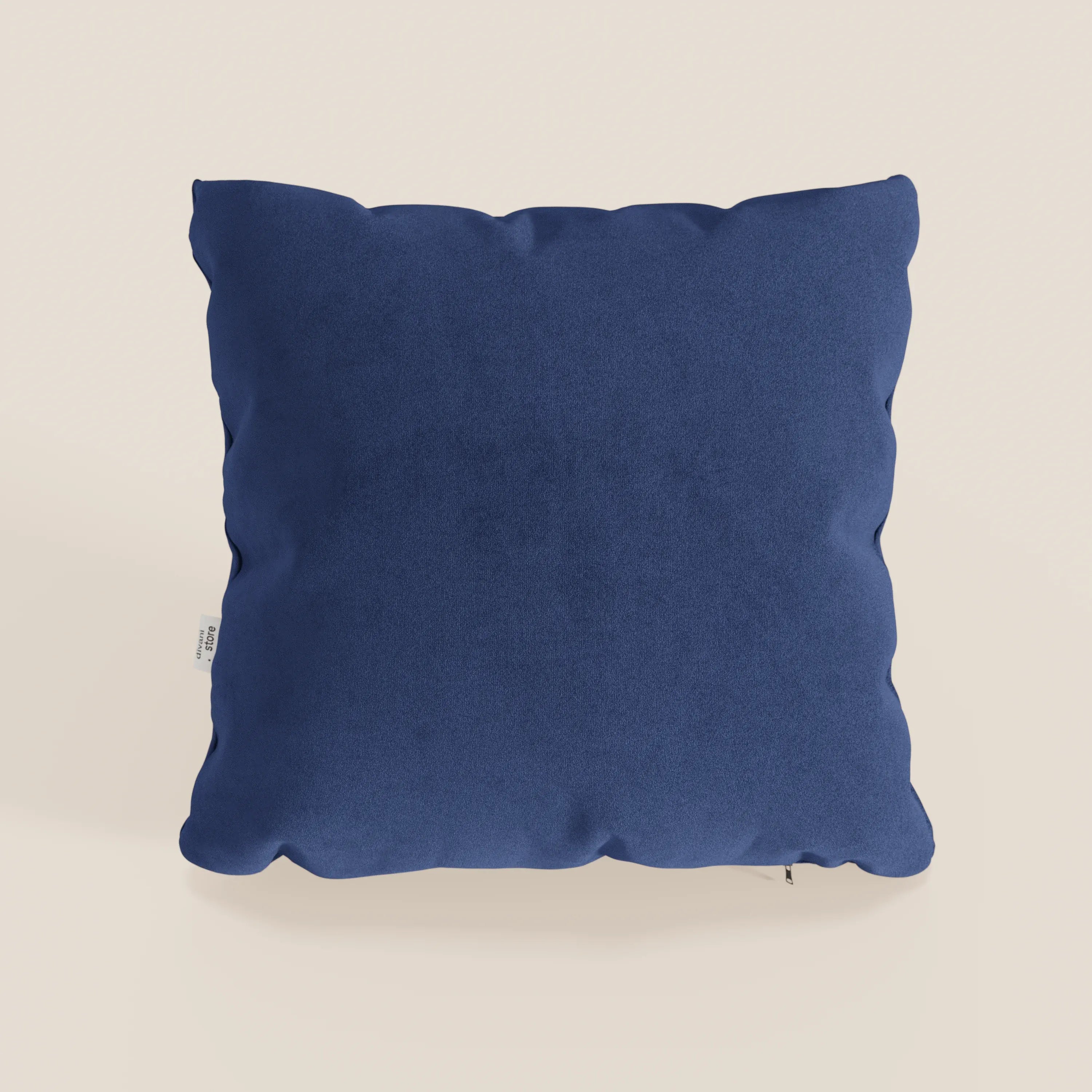 Il cuscino Jazz di Divani.Store in T11 blu, realizzato in microfibra tecnica facile da pulire, è caratterizzato da una forma quadrata con angoli arrotondati e una piccola etichetta laterale bianca, inserita in uno sfondo crema chiaro che ne sottolinea l'aspetto felpato.