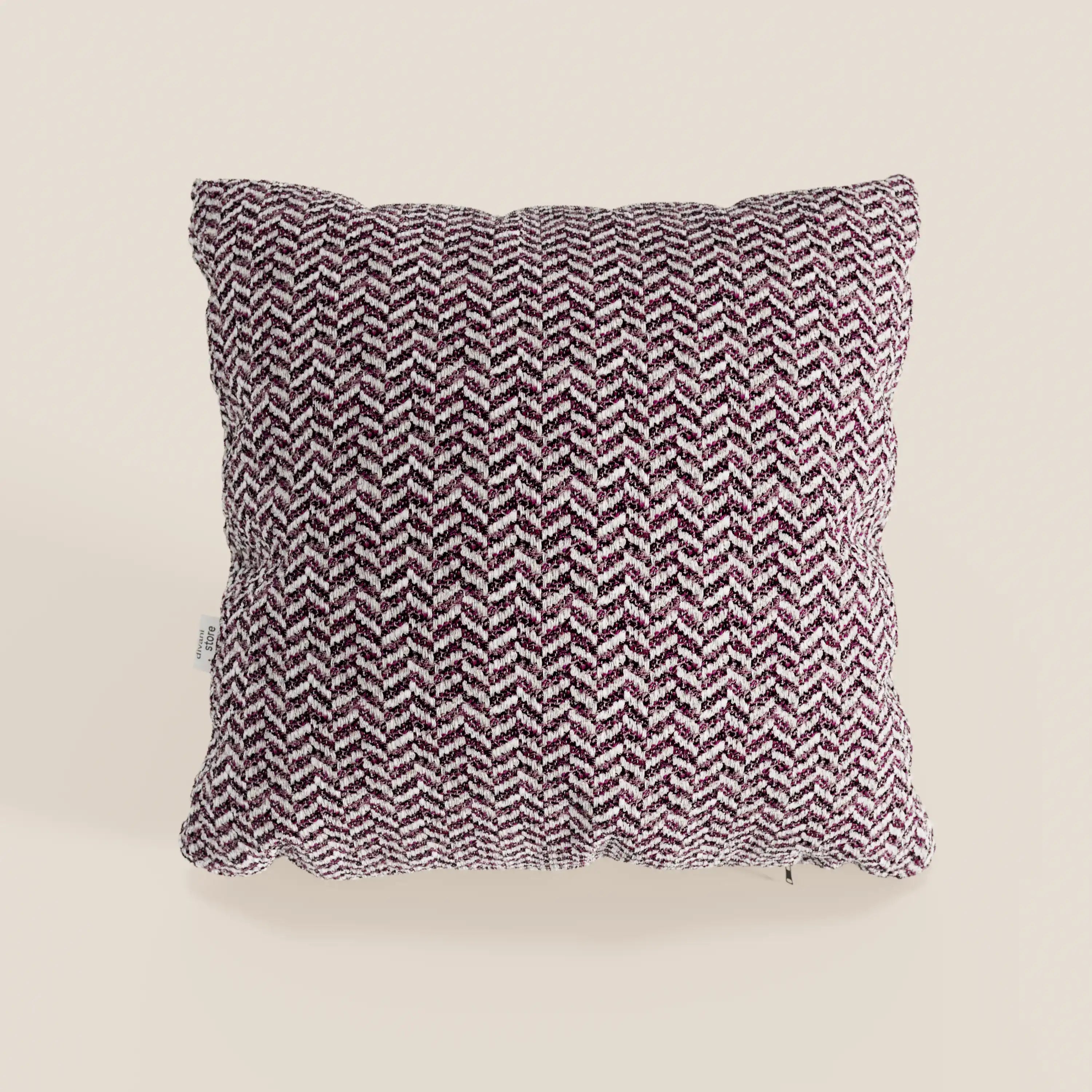 Il cuscino Sorrento 45x45 in lino di Divani.Store è un cuscino quadrato con un motivo a zig-zag in rilievo nei toni del viola scuro e del bianco su fondo beige chiaro, ispirato al design Nautilus. Presenta una piccola etichetta bianca sul lato che aggiunge un tocco di stile.
