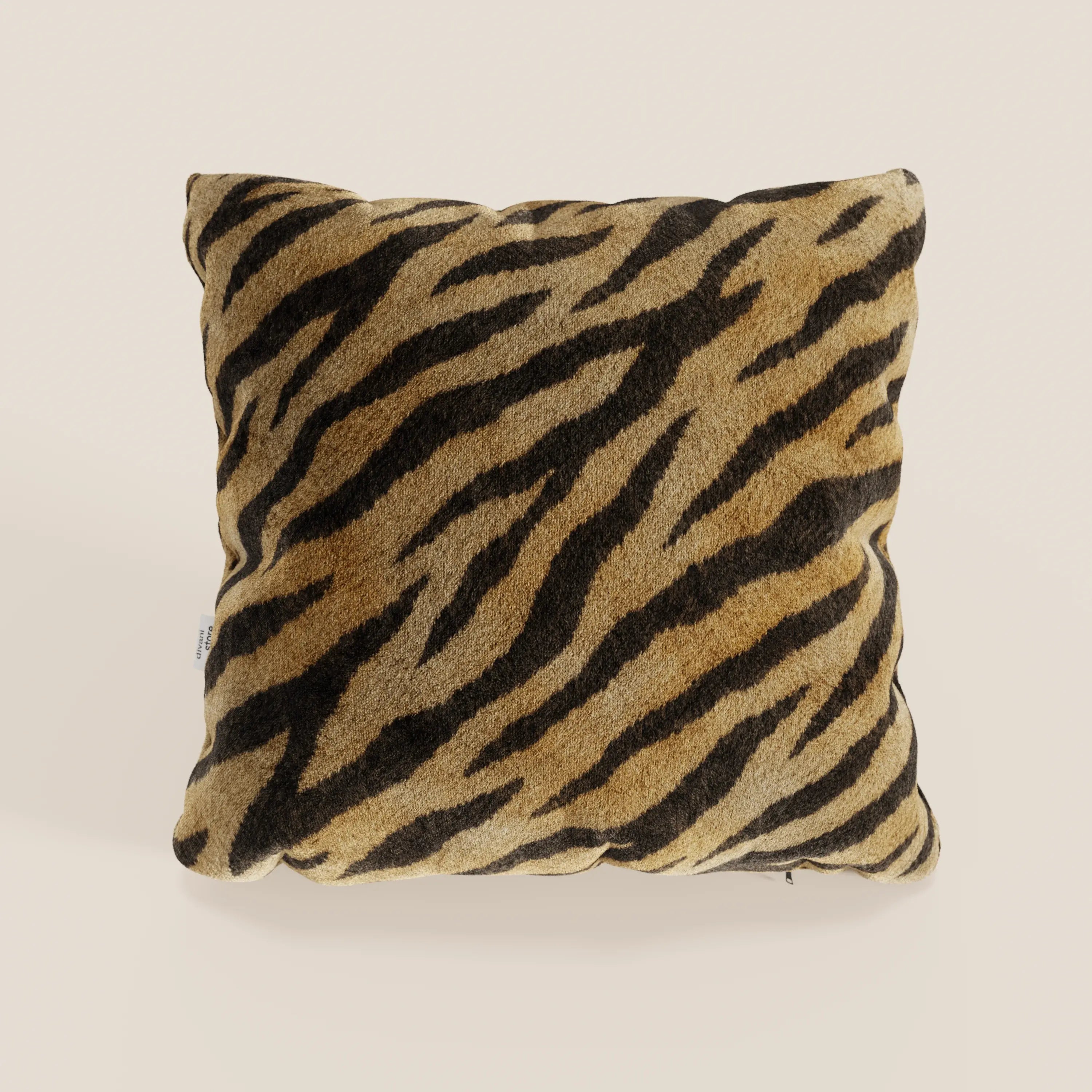 Il cuscino Wild di Divani.Store è un cuscino quadrato in microfibra impermeabile con un motivo realistico a strisce di tigre marrone, marrone e nero, una morbida texture pelosa, una fodera sfoderabile e lavabile e uno sfondo beige chiaro.
