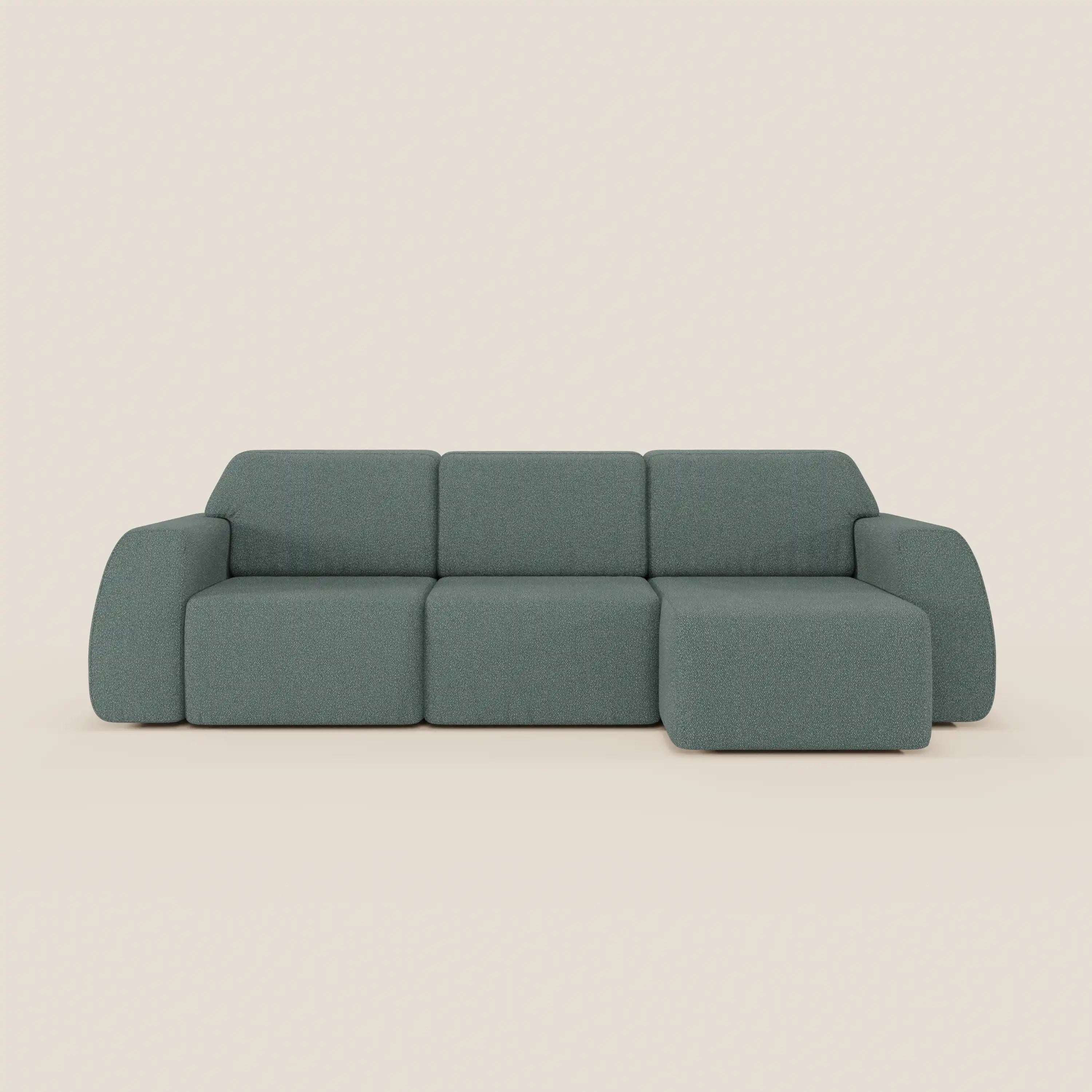 Il Divano angolare Orbit di Divani.Store è caratterizzato da un moderno design modulare con tre cuscini di seduta e una chaise reversibile, rivestiti in morbido tessuto verde effetto cotone T33 antimacchia. Su uno sfondo beige chiaro.