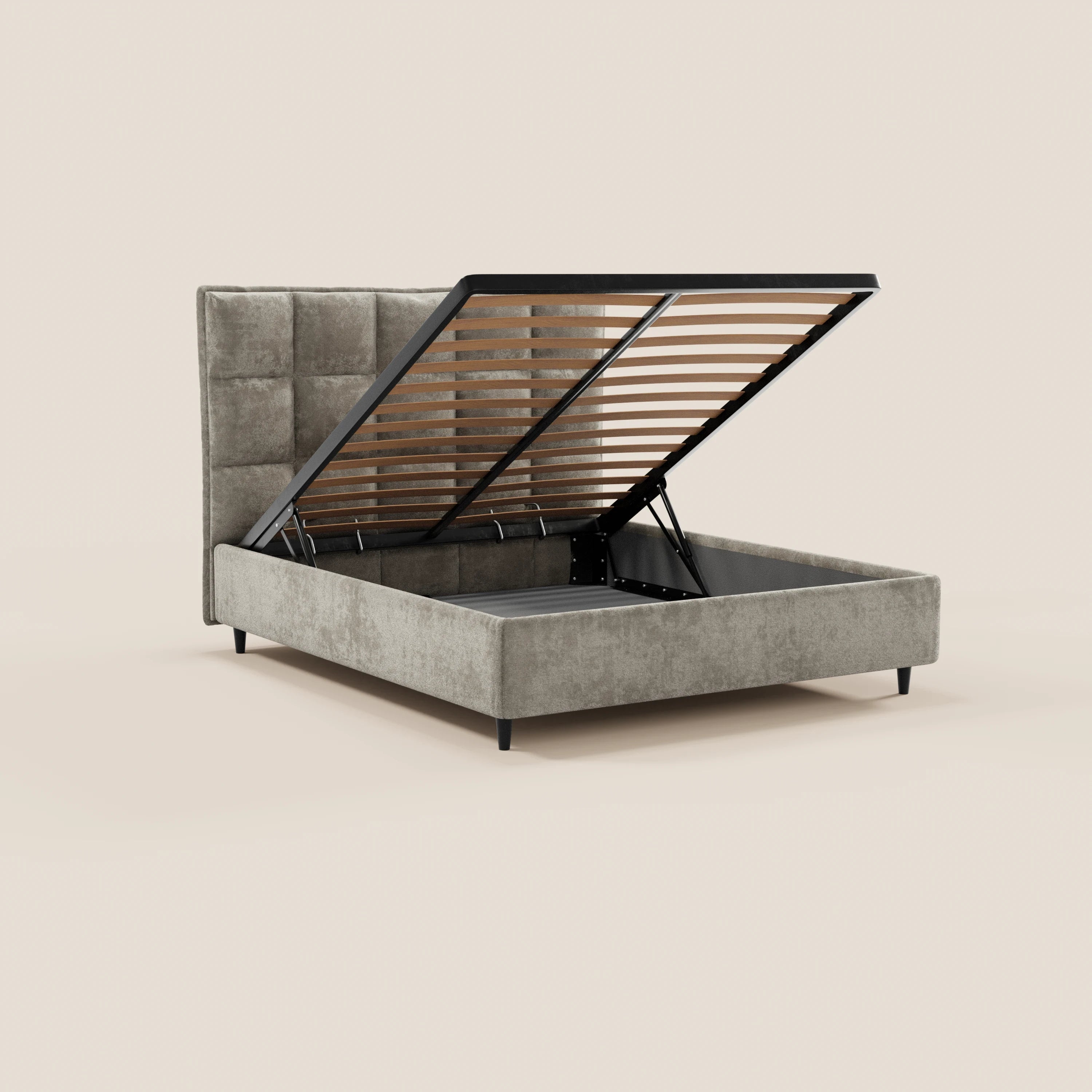Il letto imbottito AURO con contenitore e testiera alta capitonné in ciniglia Oeko-Tex® di Letti.store presenta una testiera alta e capitonné di colore grigio che, una volta sollevata, rivela un ampio spazio contenitivo; il letto poggia su quattro gambe corte nere su uno sfondo beige.