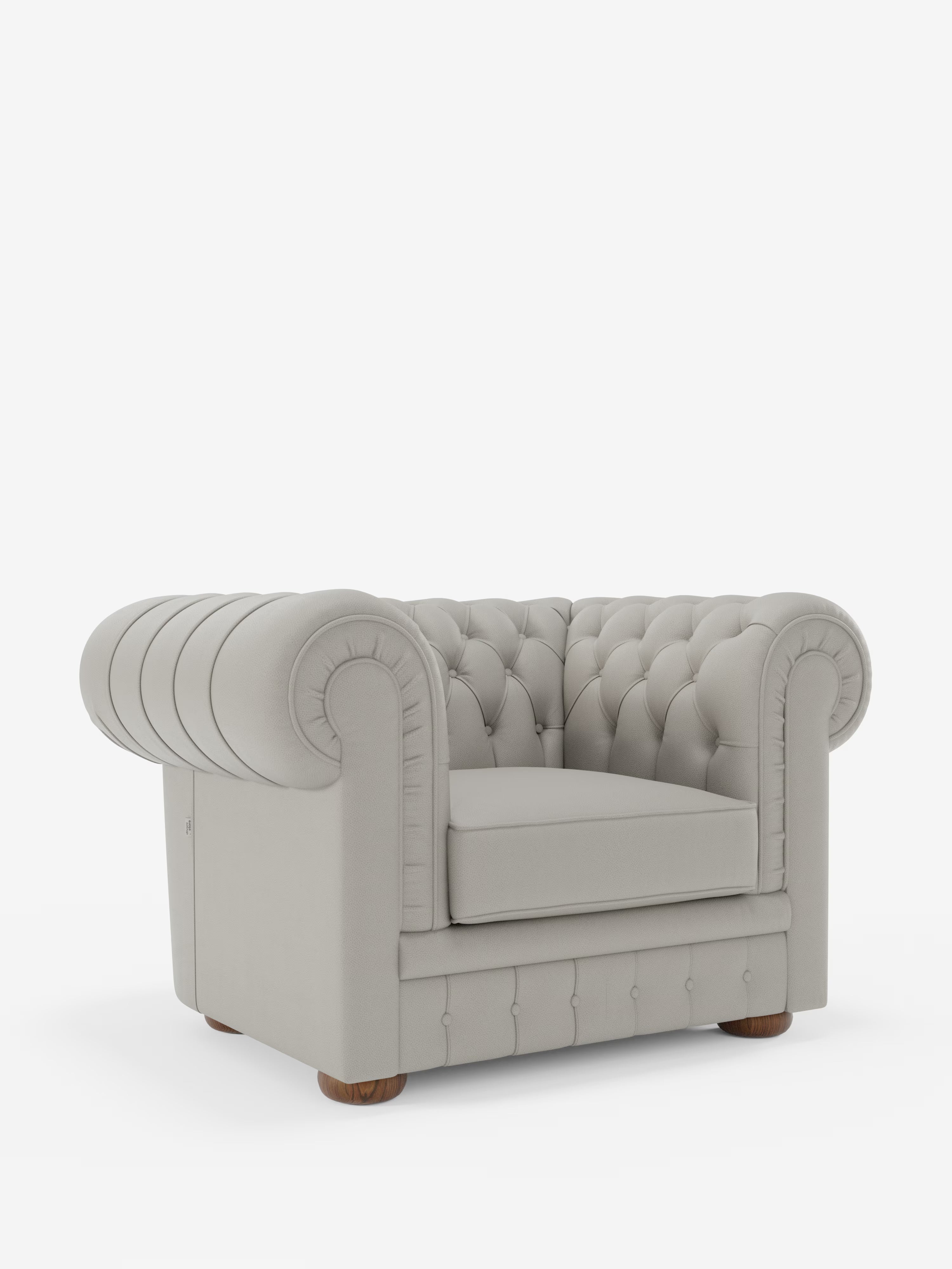 Una lussuosa poltrona Chester in vera pelle spessorata con capitonné artigianale di Divani.Store, caratterizzata da un morbido rivestimento grigio chiaro, da una profonda trapuntatura realizzata a mano in raffinato stile capitonné, da eleganti braccioli arrotondati e da robusti piedini in legno, è messa in risalto su uno sfondo bianco a tinta unita. La morbida pelle e la silhouette classica della poltrona evocano l’eleganza senza tempo del design tradizionale italiano.