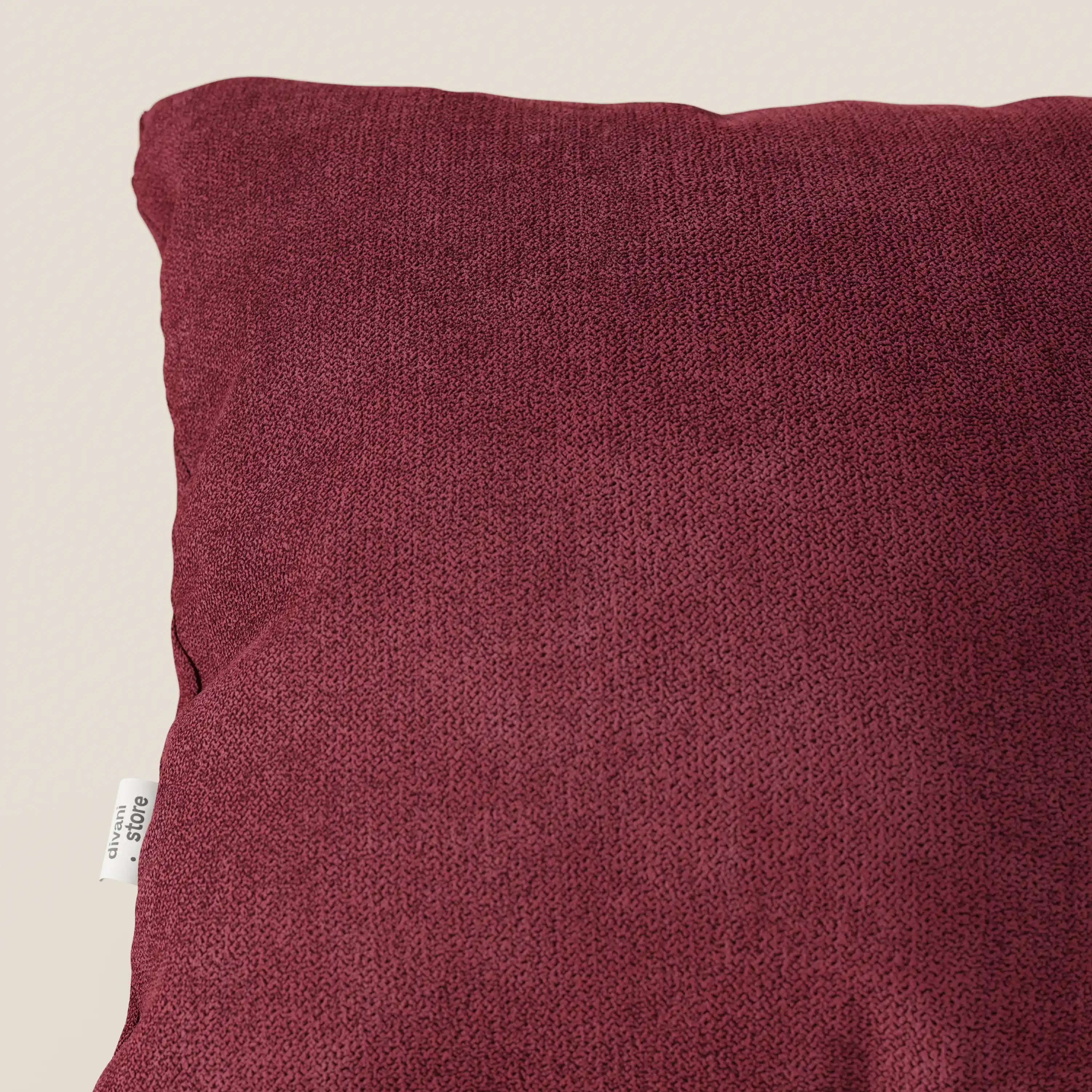 Primo piano del cuscino Destiny di Divani.Store, disponibile in T02 rosso tessuto morbido impermeabile, su sfondo beige. Il cuscino presenta un sottile motivo, una fodera lavabile e una piccola etichetta bianca sul bordo sinistro.