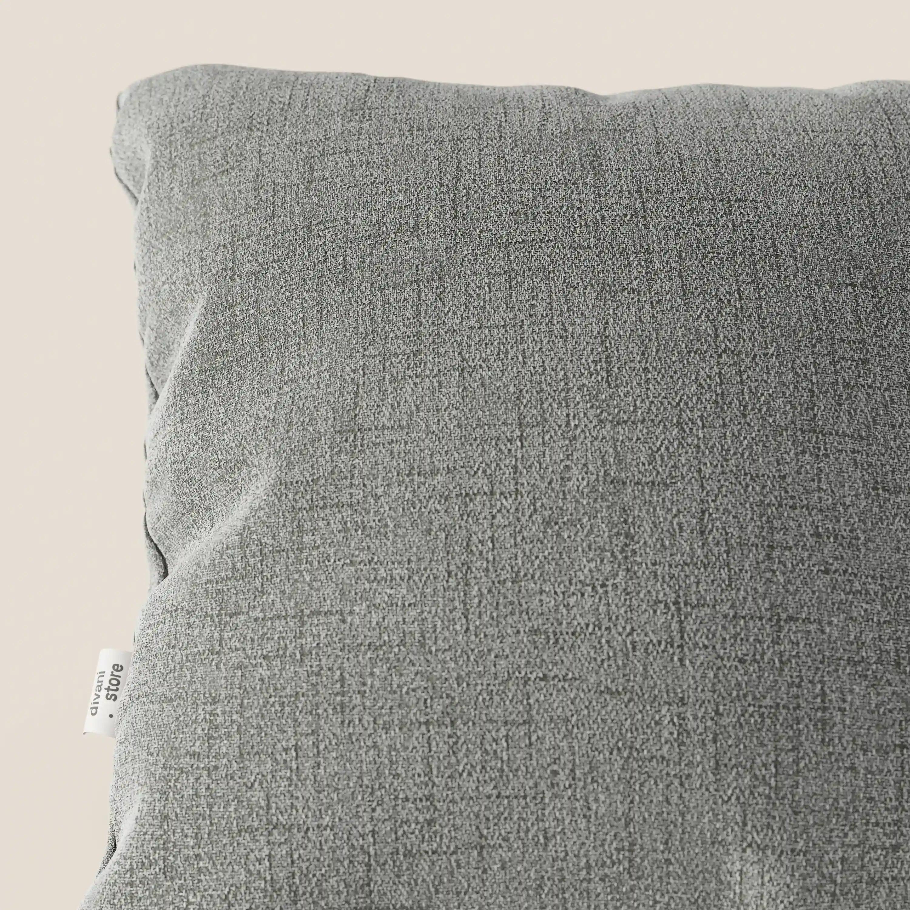 Primo piano di un cuscino Felis Divani.Store in tessuto morbido impermeabile T03 grigio chiaro con una sottile trama. Una piccola etichetta bianca appare sul bordo sinistro su uno sfondo beige chiaro.