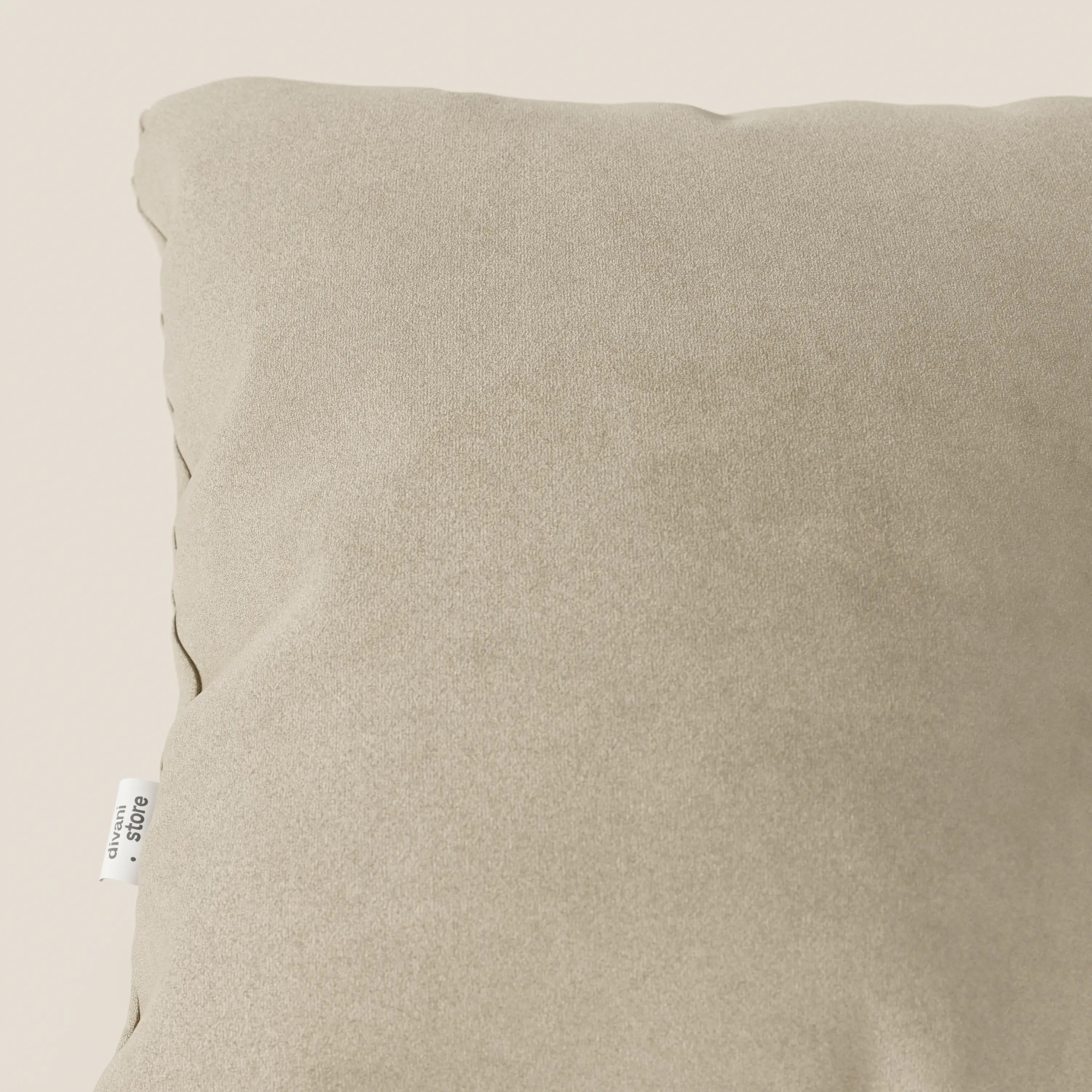 Primo piano dell'angolo superiore sinistro del cuscino Jazz 45x45 cm in microfibra tecnica smacchiabile T11 beige di Divani.Store, caratterizzato da una texture morbida e liscia e da una piccola etichetta in tessuto bianco con testo nero sulla cucitura.