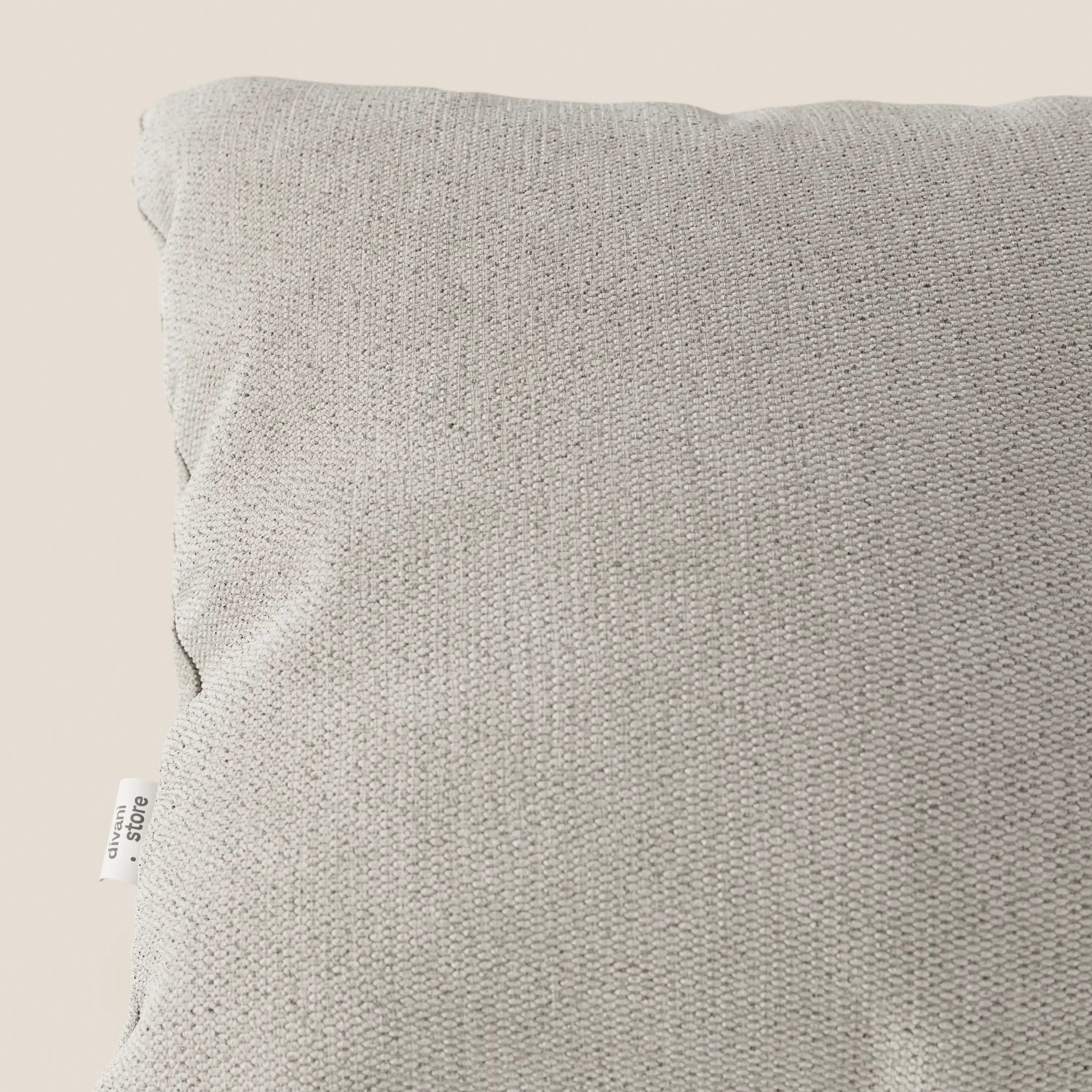 Primo piano del cuscino Miami di Divani.Store in tessuto impermeabile T14 panna, caratterizzato da una morbida texture del coperchio e da un'etichetta bianca. La fodera lavabile facilita la pulizia; qui è raffigurata su uno sfondo chiaro. Disponibile in diversi colori.