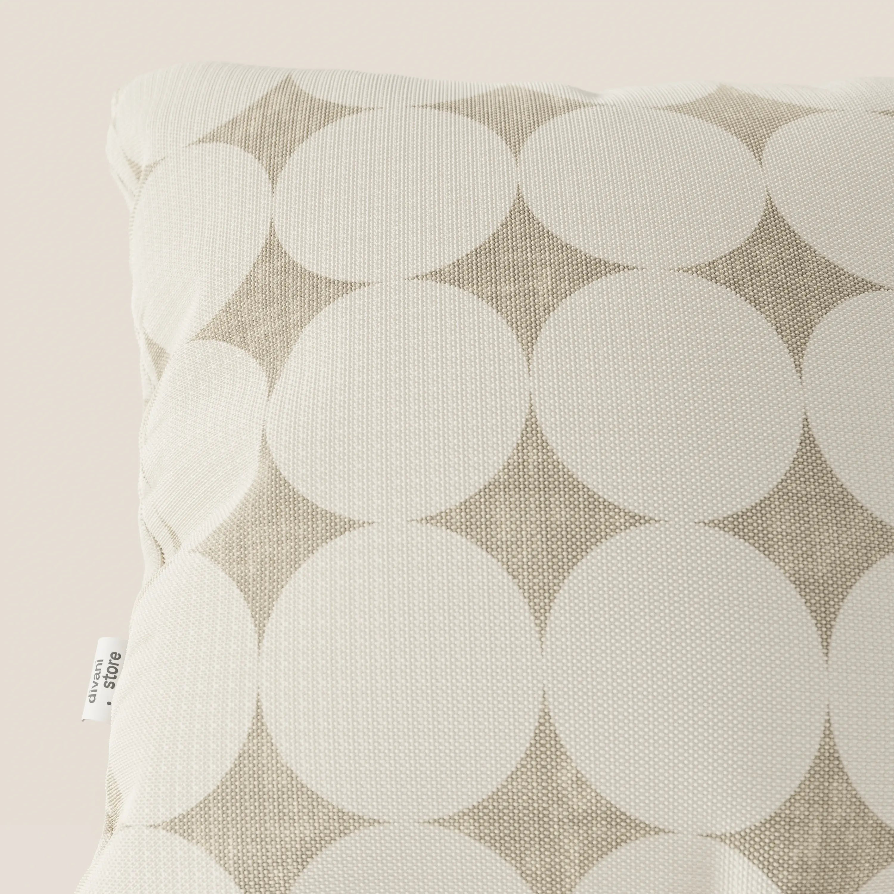 Primo piano del cuscino geometrico Dot di Divani.Store, che presenta un tessuto idrorepellente bianco con grandi cerchi sovrapposti color crema su sfondo beige e un'etichetta laterale visibile.