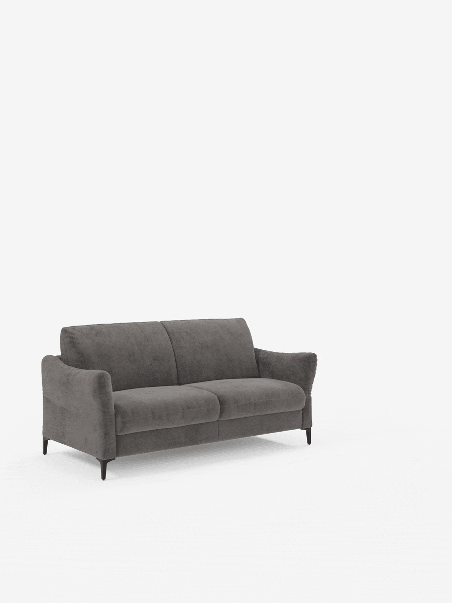 Un moderno divano letto a due posti “Dalia” di Divani.Store, color grigio scuro, rivestito in tessuto vellutato T30 antimacchia, caratterizzato da sottili gambe nere e posizionato su uno sfondo bianco. Il divano presenta braccioli leggermente inclinati, morbidi cuscini di seduta e schienali leggermente angolati. Non sono visibili altri oggetti o decorazioni.