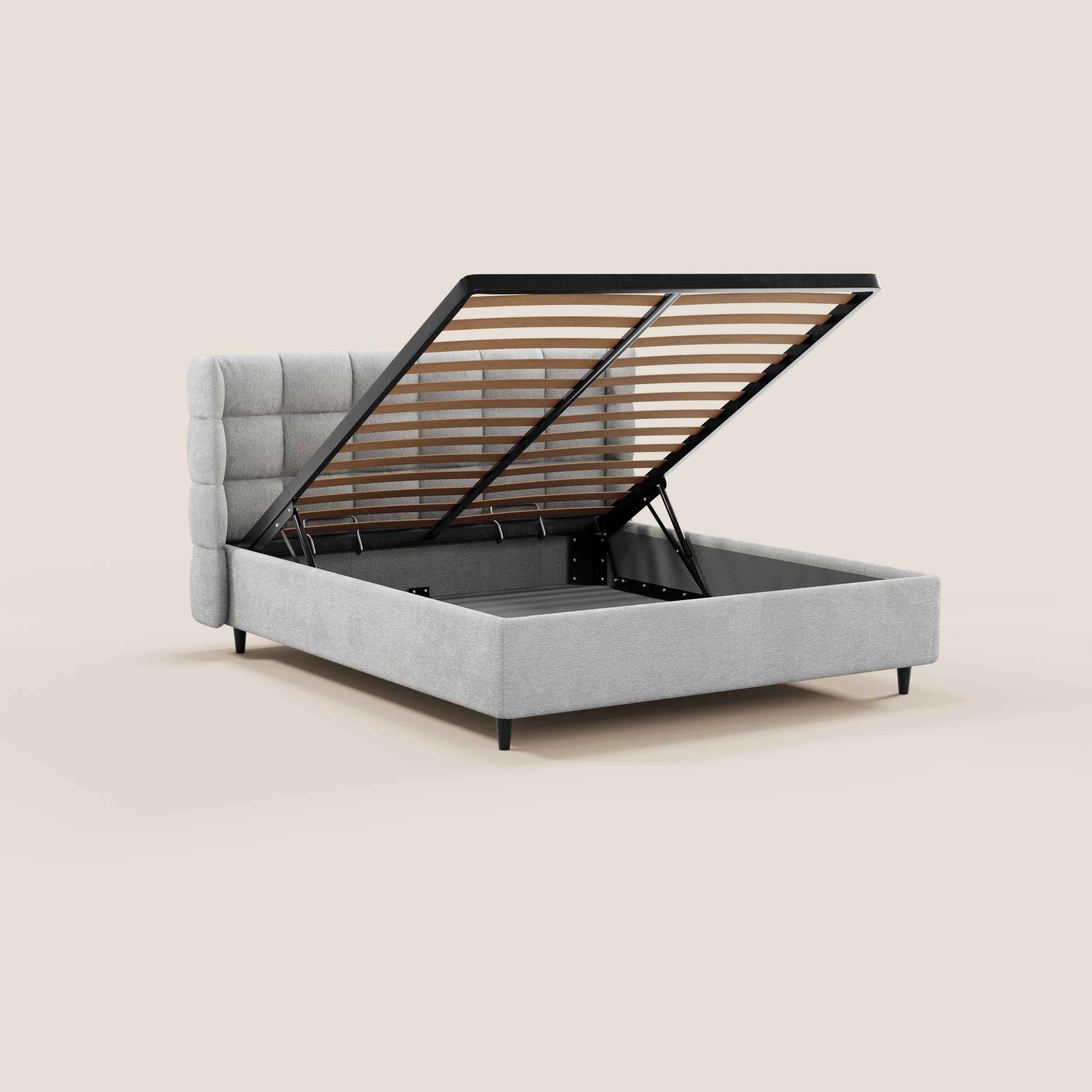 Il letto imbottito RAGNAR di Letti.store presenta una testiera capitonné avvolgente, una base con contenitore a sollevamento e sottili gambe nere, realizzate in un elegante tessuto certificato Oeko-Tex®, qui raffigurato in grigio chiaro su uno sfondo beige a tinta unita.