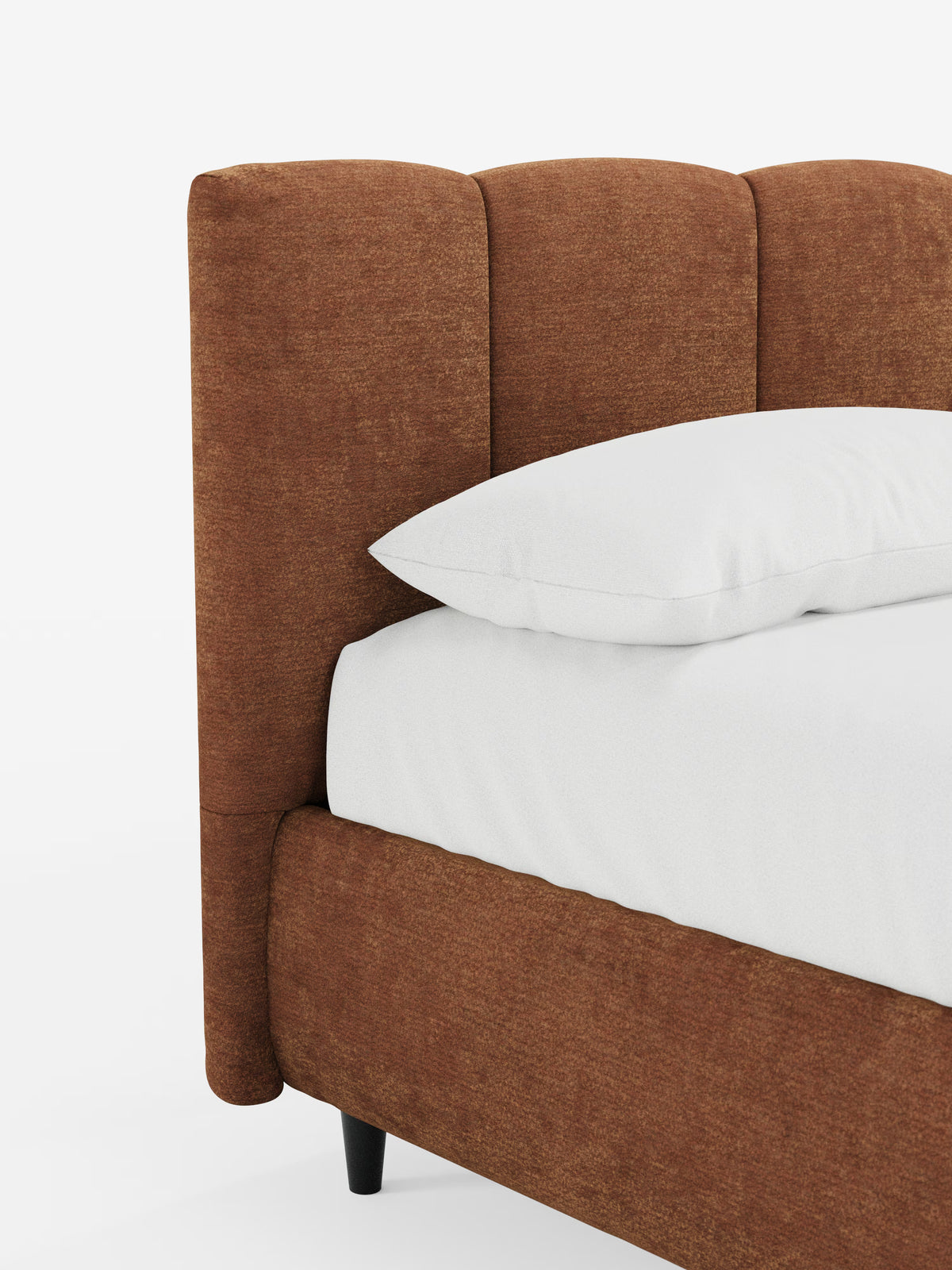 Primo piano del letto imbottito ARKAM con contenitore e testiera a cuciture verticali di Letti.store. Il letto, rivestito in tessuto marrone certificato Oeko-Tex®, presenta una testiera imbottita con cuciture verticali e un design in stile shabby chic. Sul materasso poggiano un cuscino bianco e biancheria da letto bianca, mentre la struttura poggia su corte gambe affusolate nere che si stagliano su uno sfondo bianco a tinta unita. L’estetica complessiva è moderna e minimalista.