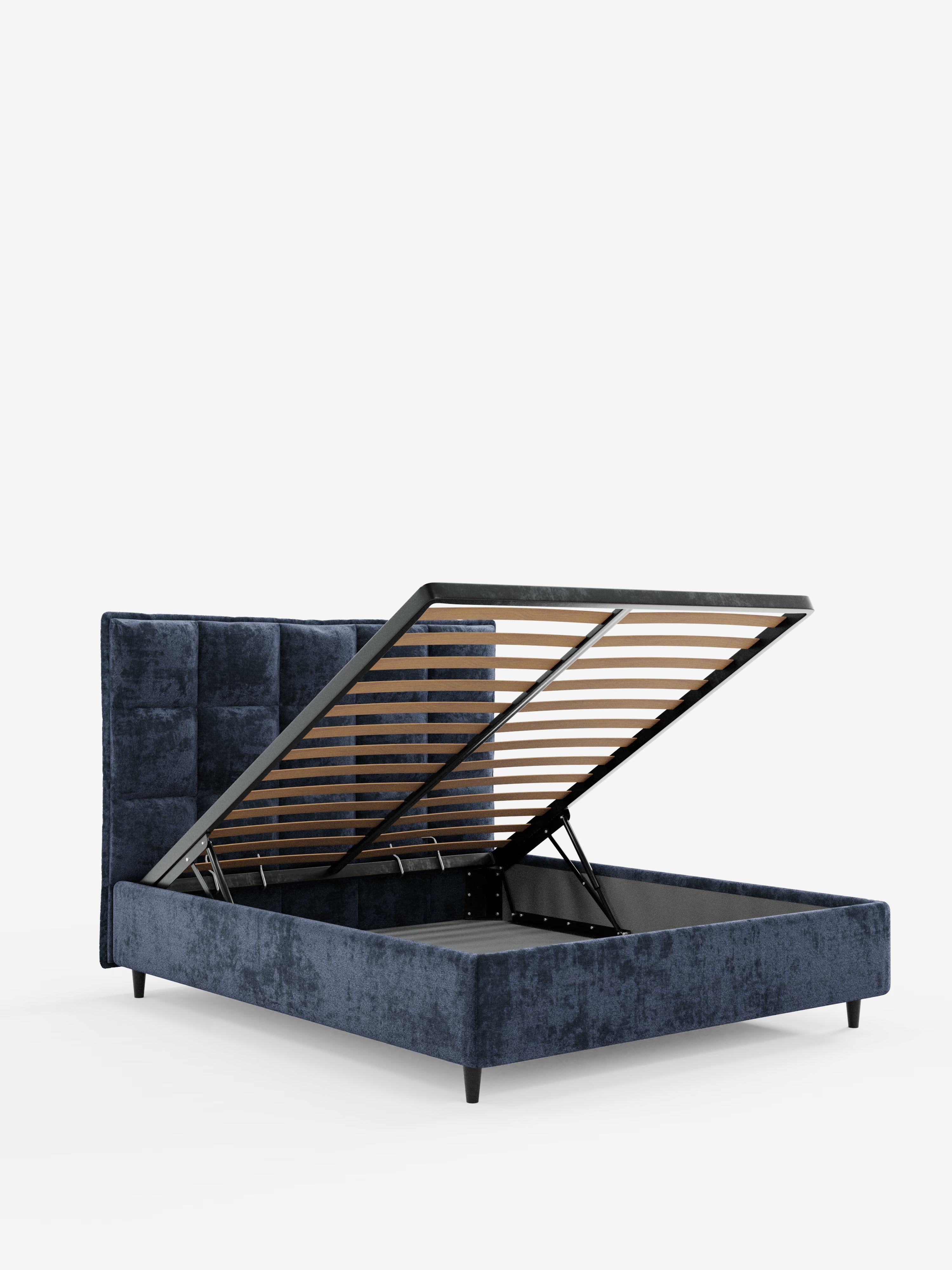 Vi presentiamo AURO di Letti.store: un moderno letto imbottito con contenitore, caratterizzato da una testiera alta capitonné rivestita in ciniglia blu scuro certificata Oeko-Tex®. La base del materasso si solleva per rivelare un ampio spazio contenitore, ideale per ottimizzare lo spazio nelle camere moderne. La struttura è sostenuta da corte gambe nere e risalta su uno sfondo bianco a tinta unita.