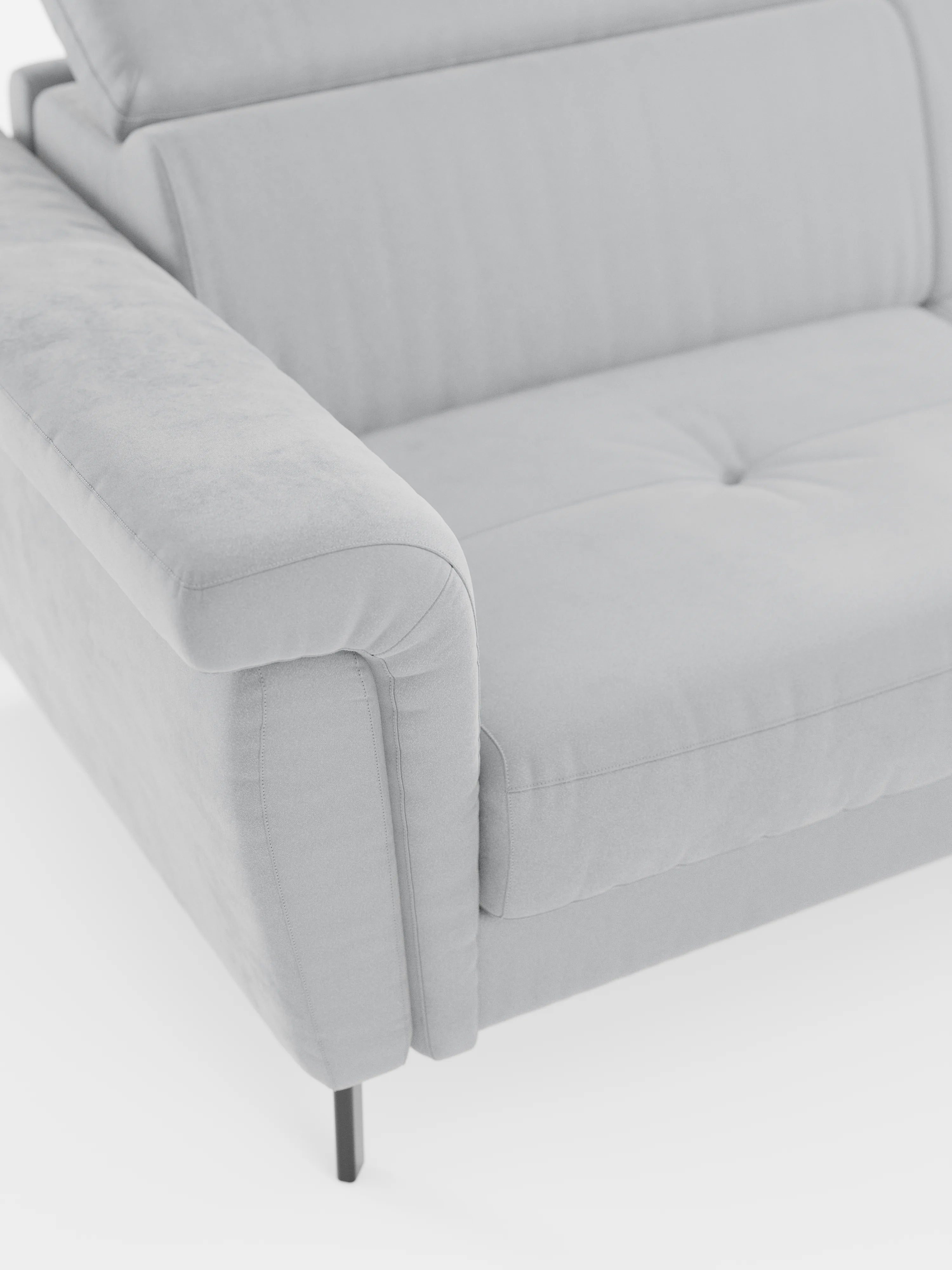 Un primo piano del divano letto di design Capri di Divani.Store, caratterizzato da un rivestimento grigio chiaro in raffinato tessuto effetto velluto smacchiabile T30, moderni braccioli morbidi e arrotondati, cuscini di seduta trapuntati e sottili piedini alti in metallo nero. Il lato sinistro e parte della zona di seduta sono visibili su uno sfondo bianco, che mette in risalto la raffinata manifattura italiana e i poggiatesta reclinabili.
