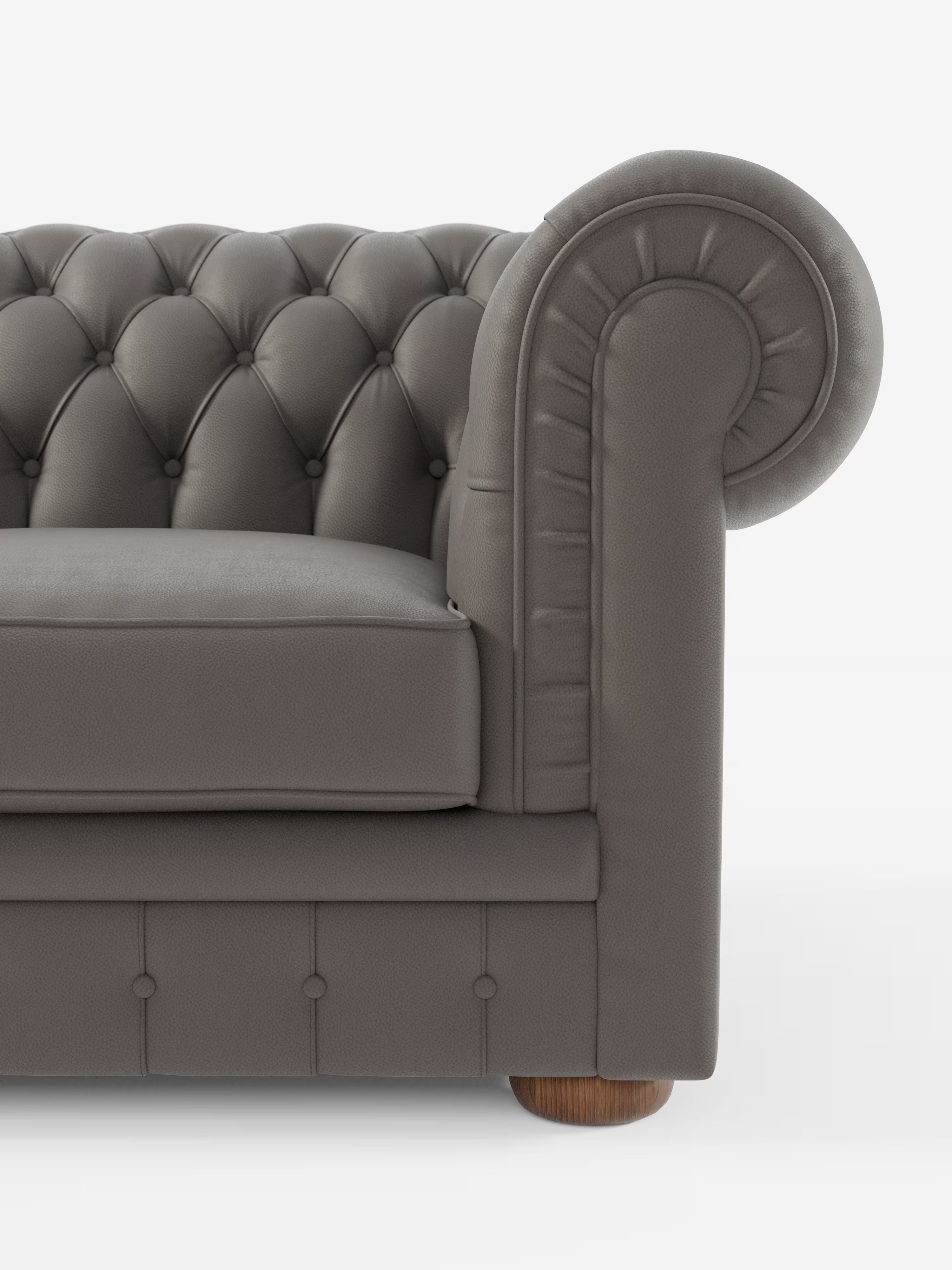 Un primo piano del Chester – Divano Chesterfield in vera pelle spessorata a 2 e 3 posti di Divani.Store mostra la metà sinistra di questo elegante divano italiano realizzato a mano. L’immagine mostra un bracciolo grigio trapuntato dal design arrotondato, una seduta imbottita, dettagli con bottoni e una gamba cilindrica in legno su sfondo bianco.