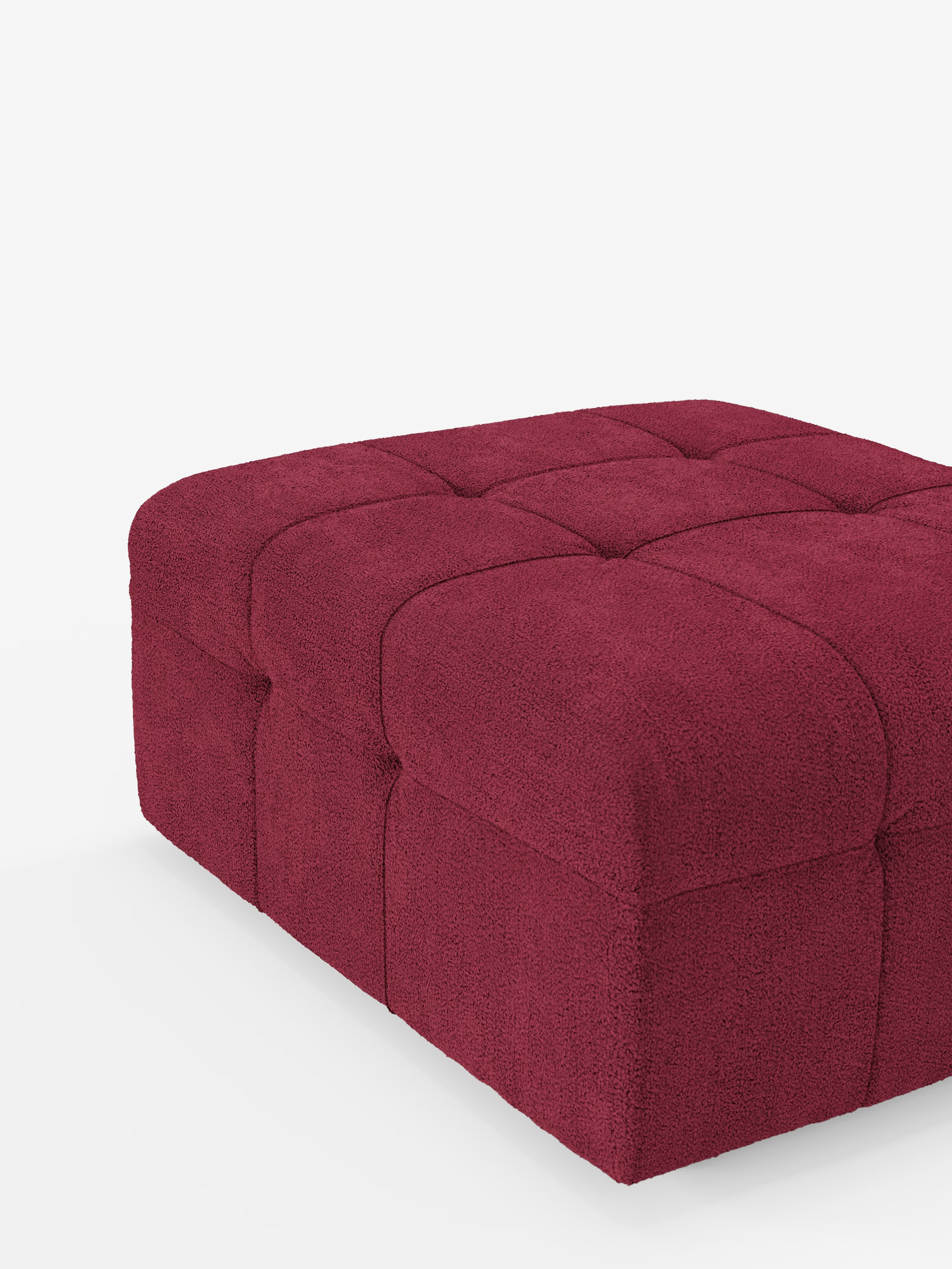 Un pouf quadrato di Divani.Store, il “Mosaic pouf e modulo in bouclé - 96x77 cm design capitonné in tessuto smacchiabile T21”, rivestito in un ricco tessuto bouclé color bordeaux scuro dalla trama marcata. Ispirato a un elegante pouf a mosaico, presenta cuciture a vista che formano ampie sezioni quadrate sulla parte superiore e sui lati. Il prodotto è ripreso su uno sfondo bianco a tinta unita.