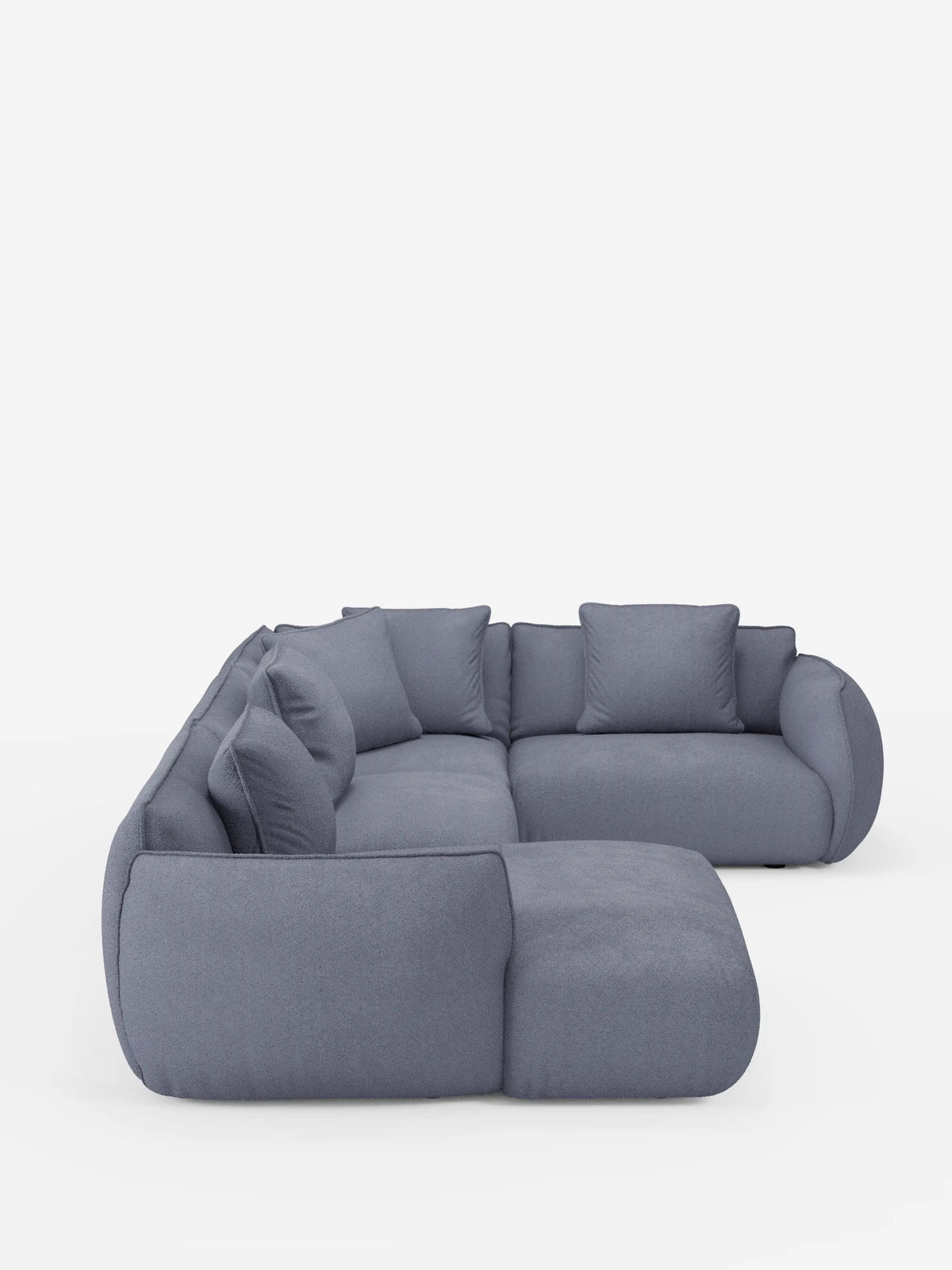 Il divano angolare panoramico componibile Nimbus con penisola e angolo in tessuto smacchiabile T33 di Divani.Store presenta morbidi cuscini arrotondati e sei cuscini quadrati coordinati, disposti con eleganza a forma di L su uno sfondo bianco a tinta unita. Questo divano moderno vanta braccioli e schienali morbidi e sinuosi che mettono in risalto la raffinatezza dell’artigianato italiano — orgogliosamente realizzato in Italia.