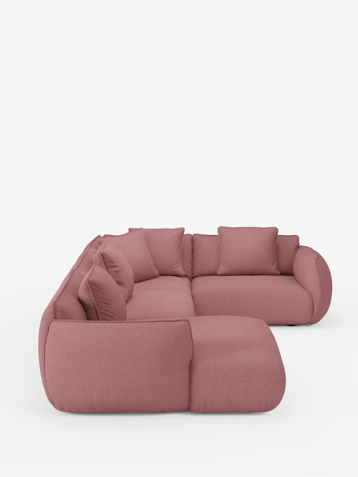 Un moderno divano angolare panoramico componibile Nimbus con penisola e angolo in tessuto smacchiabile T33 di Divani.Store, rivestito in tessuto rosa tenue e caratterizzato da cinque grandi cuscini dello schienale e ampi braccioli arrotondati, su uno sfondo bianco a tinta unita.