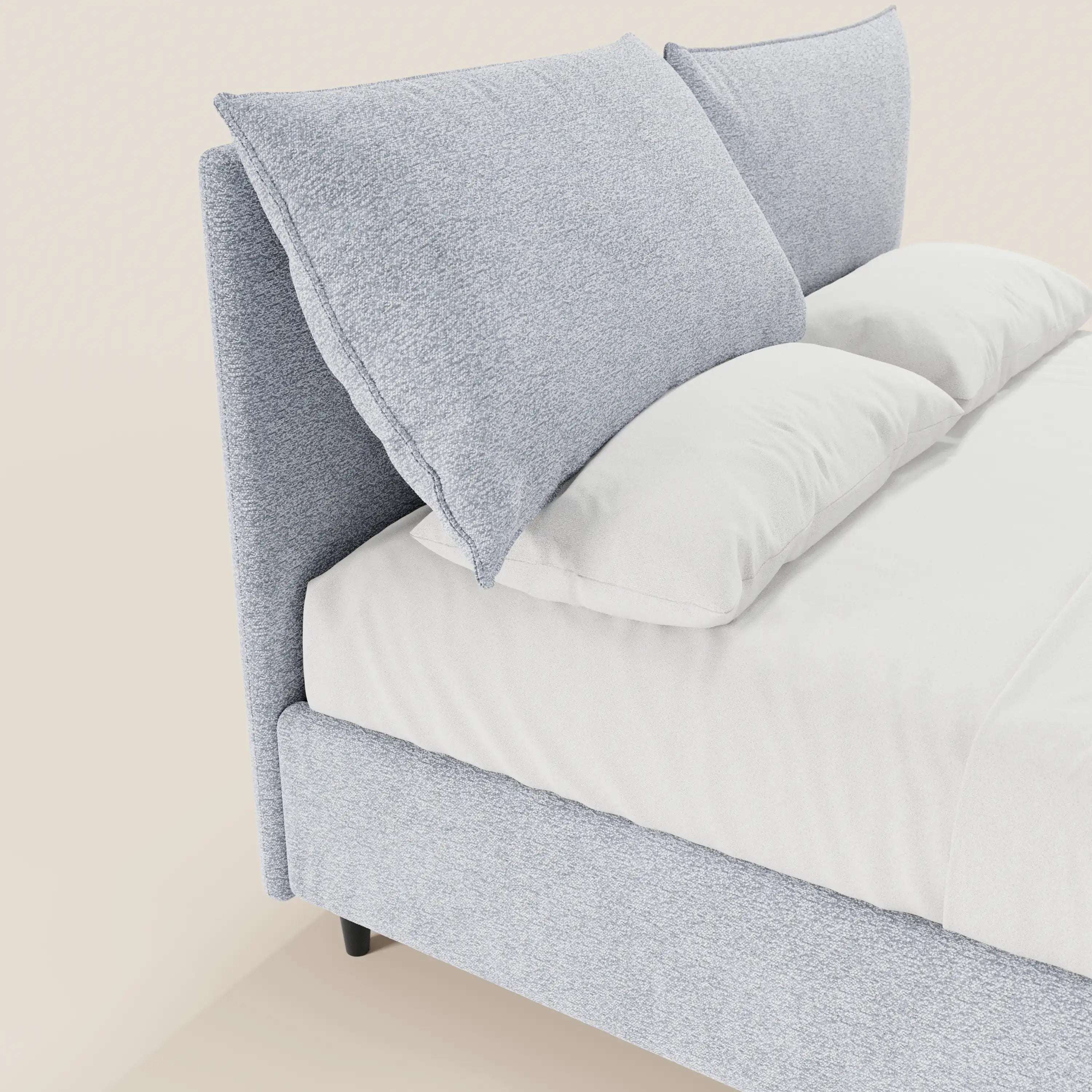 Un primo piano del letto imbottito ZAYRON di Letti.store, caratterizzato da una struttura moderna in tessuto certificato Oeko-Tex® con base contenitiva e morbidi cuscini regolabili, abbinato a biancheria da letto bianca su uno sfondo a tinta unita per un look minimalista.