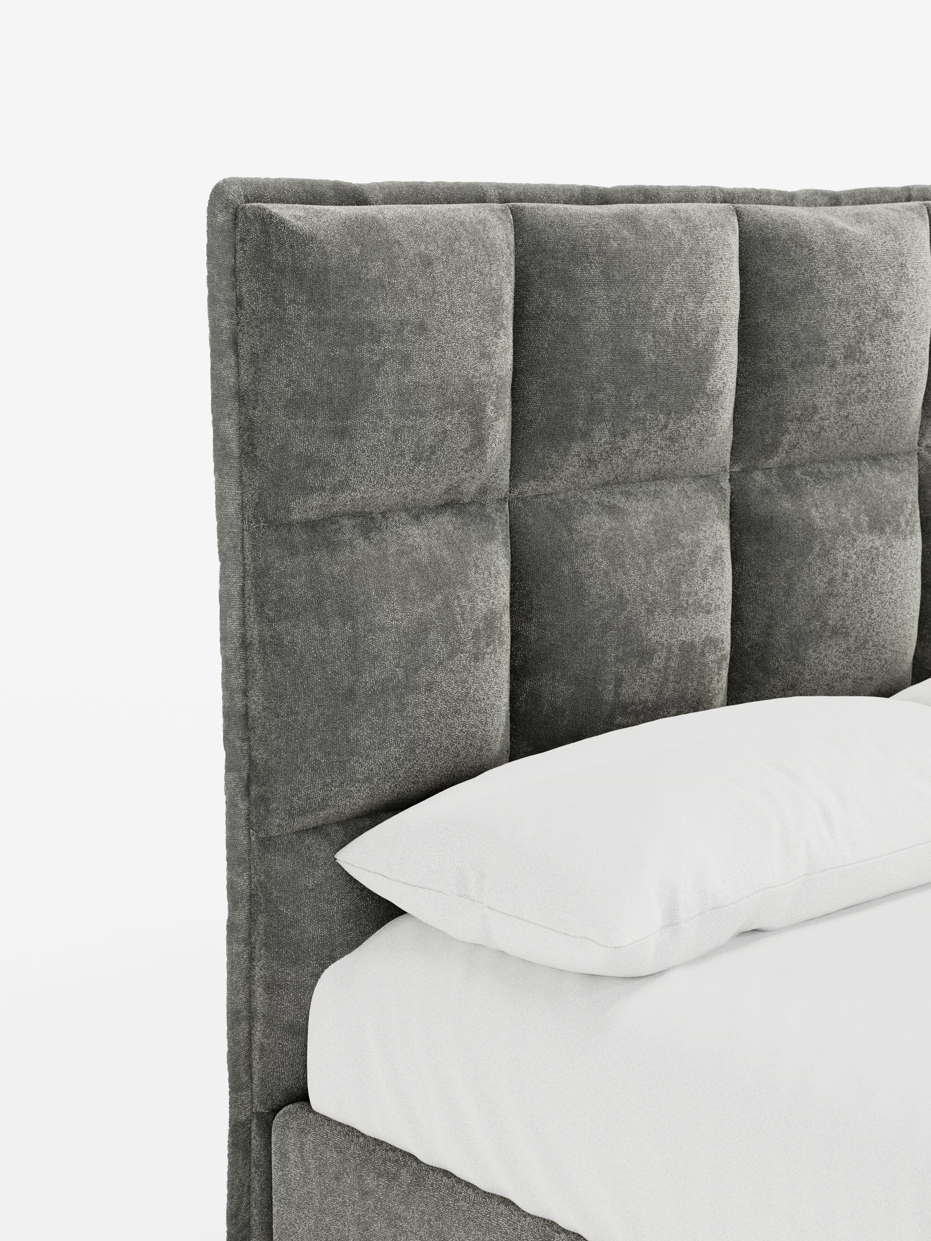 Ecco una versione rielaborata della frase utilizzando i dati del tuo prodotto: Un primo piano del letto imbottito AURO con contenitore e testiera capitonné alta in ciniglia Oeko-Tex® di Letti.store mette in risalto la sua testiera grigia capitonné, con sezioni quadrate imbottite e la morbida trama in ciniglia. Il cuscino e il materasso bianchi risaltano sullo sfondo bianco a tinta unita, sottolineando il design moderno e minimalista del letto.