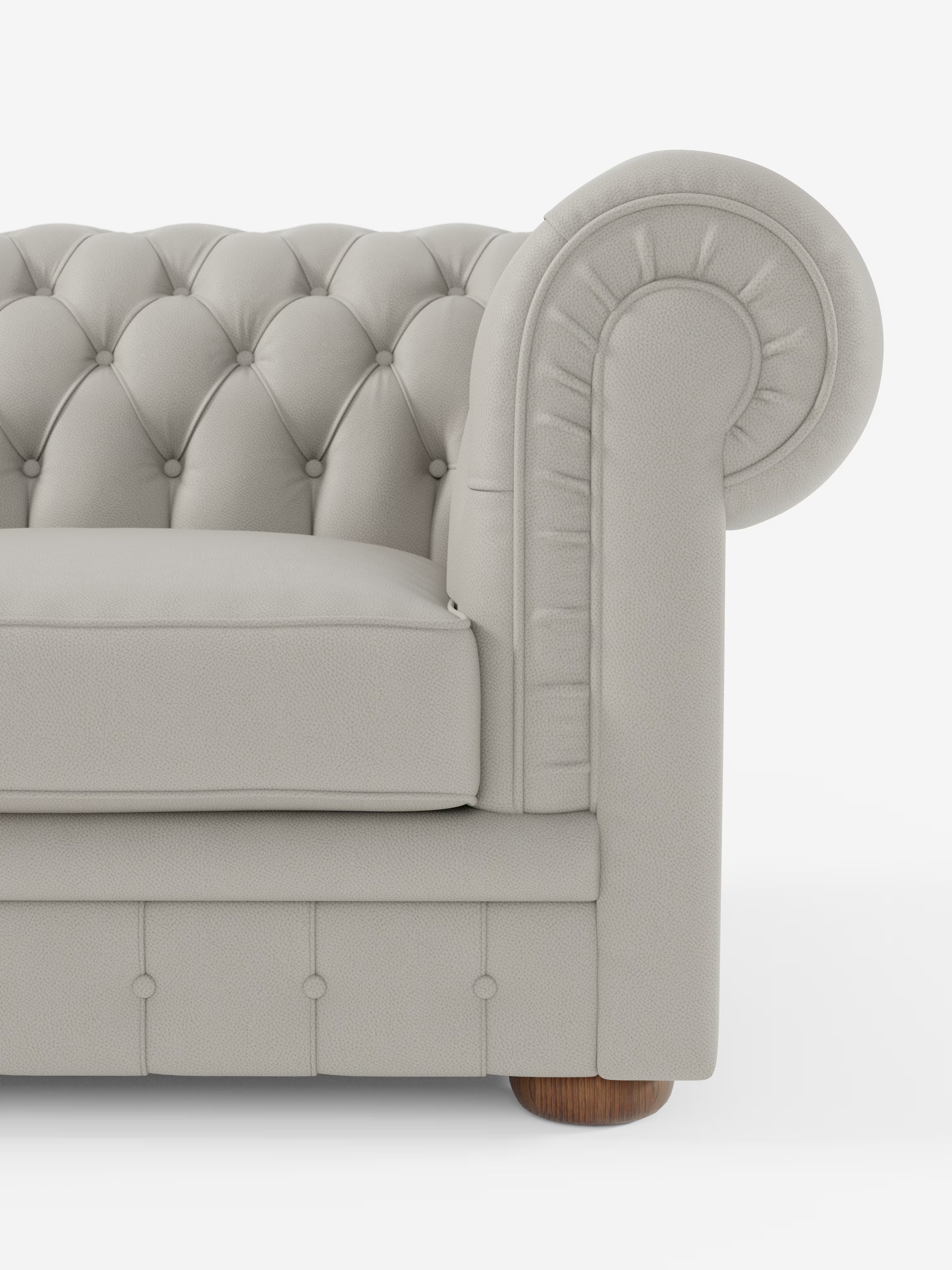 Primo piano del bracciolo del divano Chester – Divano Chesterfield in vera pelle spessorata a 2 e 3 posti di Divani.Store, che mette in risalto il rivestimento in pelle grigio chiaro con trapuntatura a bottoni e bordi arrotondati. Questo elegante divano presenta dettagli a bottoni lungo lo schienale e la base, oltre a una gamba in legno a vista, il tutto su uno sfondo bianco.