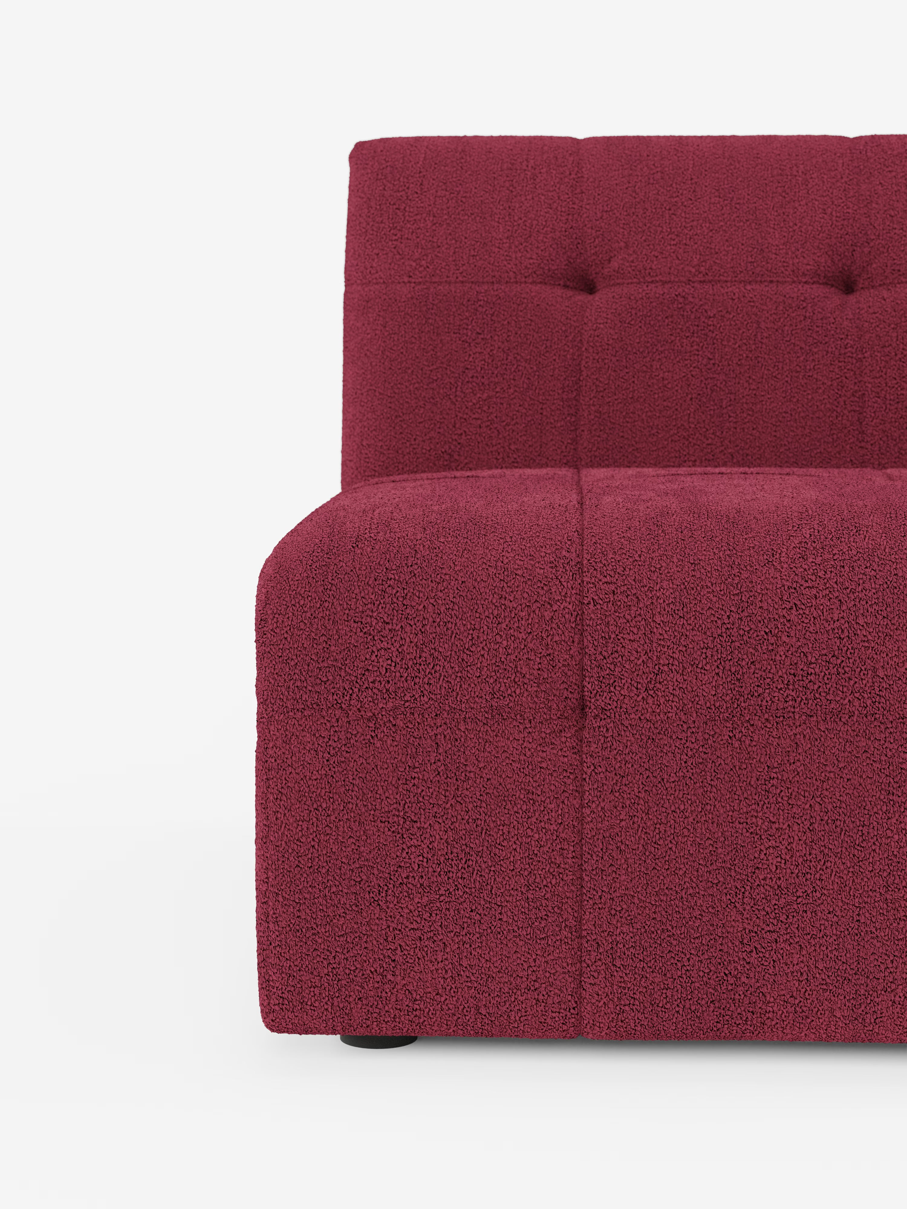 Una ripresa ravvicinata e angolata della poltrona Mosaic modulo da 77 cm di Divani.Store ne mette in risalto il moderno tessuto bouclé T21, di colore rosso intenso e resistente alle macchie, con una raffinata trapuntatura capitonné sullo schienale e sulla seduta. Su uno sfondo bianco a tinta unita sono visibili solo il lato sinistro e parte dello schienale, a sottolineare il suo sofisticato design italiano e l’eccezionale maestria artigianale del Made in Italy.