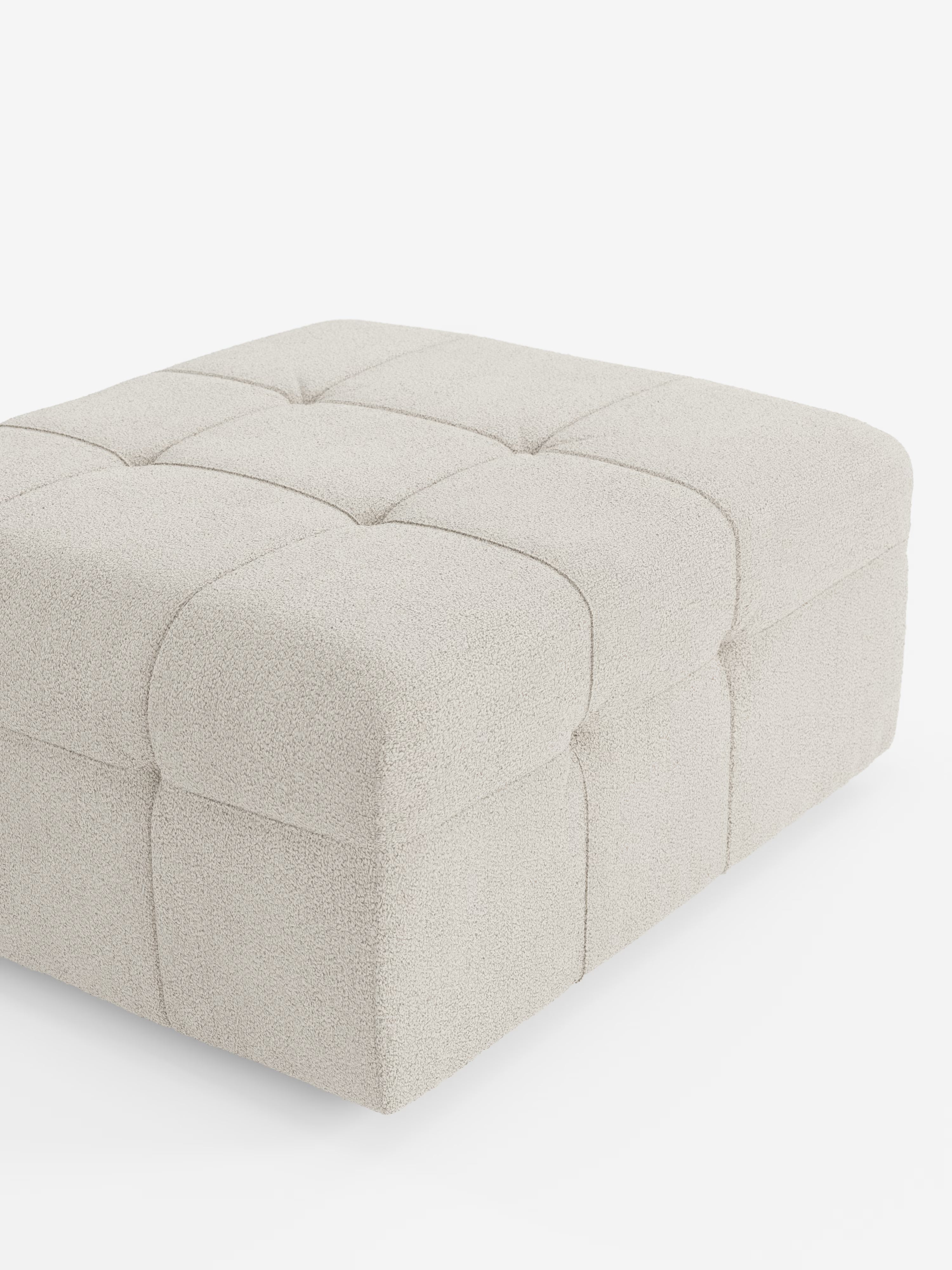 Un pouf spazioso e di forma quadrata di Divani.Store, il modello Mosaic in bouclé (96x77 cm), presenta un design capitonné in tessuto T21 resistente alle macchie. Il suo rivestimento beige chiaro a trama rigata è suddiviso in una griglia di nove quadrati leggermente trapuntati, che richiamano l’aspetto lussuoso della collezione Pouf Mosaic. Presentato su uno sfondo bianco a tinta unita.