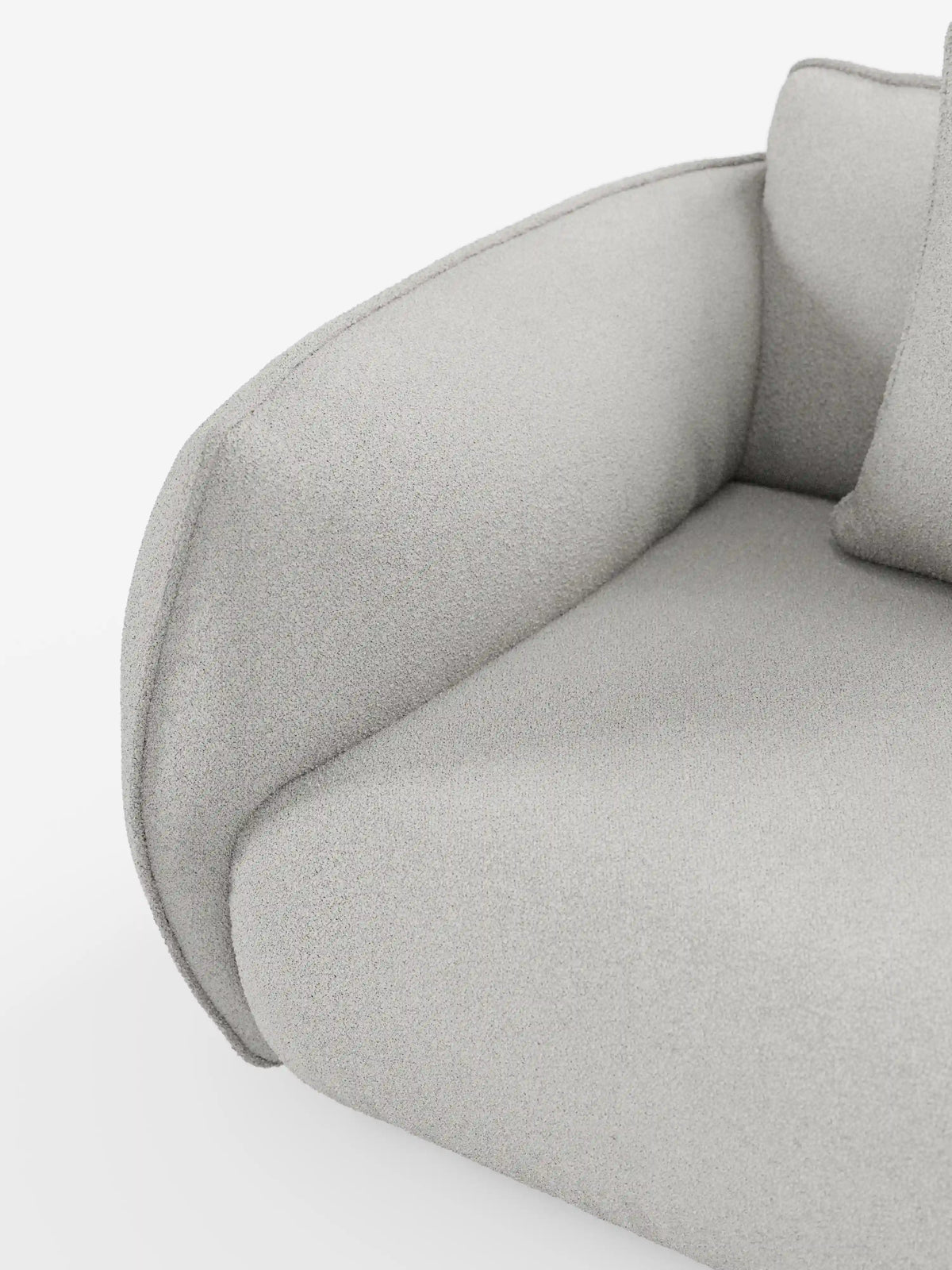 Primo piano del divano Nimbus a 3 posti, modulare e componibile, da 250 cm di Divani.Store, rivestito in tessuto smacchiabile effetto cotone T33 color grigio chiaro. L'immagine mette in risalto il bracciolo dalle curve eleganti, il cuscino di seduta e parte dello schienale, evidenziando il tessuto morbido, soffice e sfoderabile con finitura testurizzata. Le linee fluide sottolineano il design contemporaneo di questo divano versatile su uno sfondo bianco.