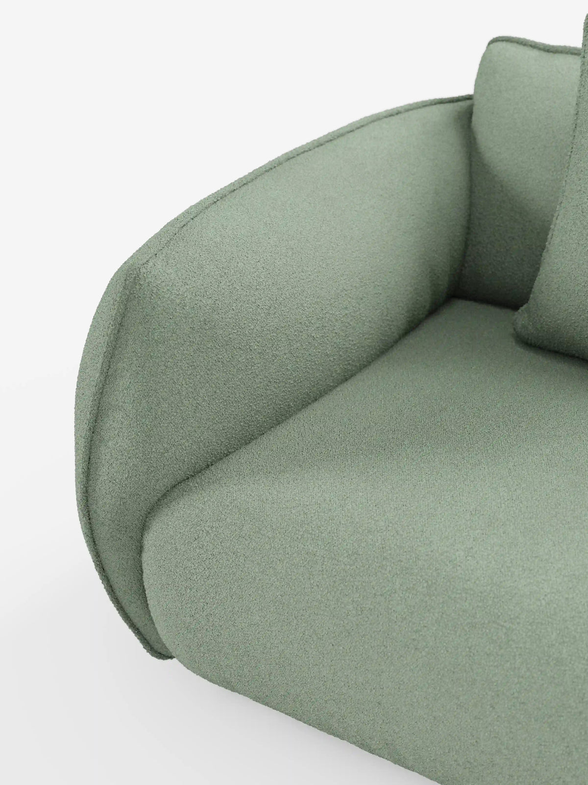 Primo piano del divano Nimbus a 3 posti, modulare e componibile, di Divani.Store, in un moderno verde salvia, rivestito in morbido tessuto effetto cotone antimacchia (tessuto smacchiabile effetto cotone t33). L'immagine mette in risalto il bracciolo ricurvo, il cuscino di seduta e parte di un cuscino su uno sfondo bianco, esaltandone il design lussuoso ma minimalista.
