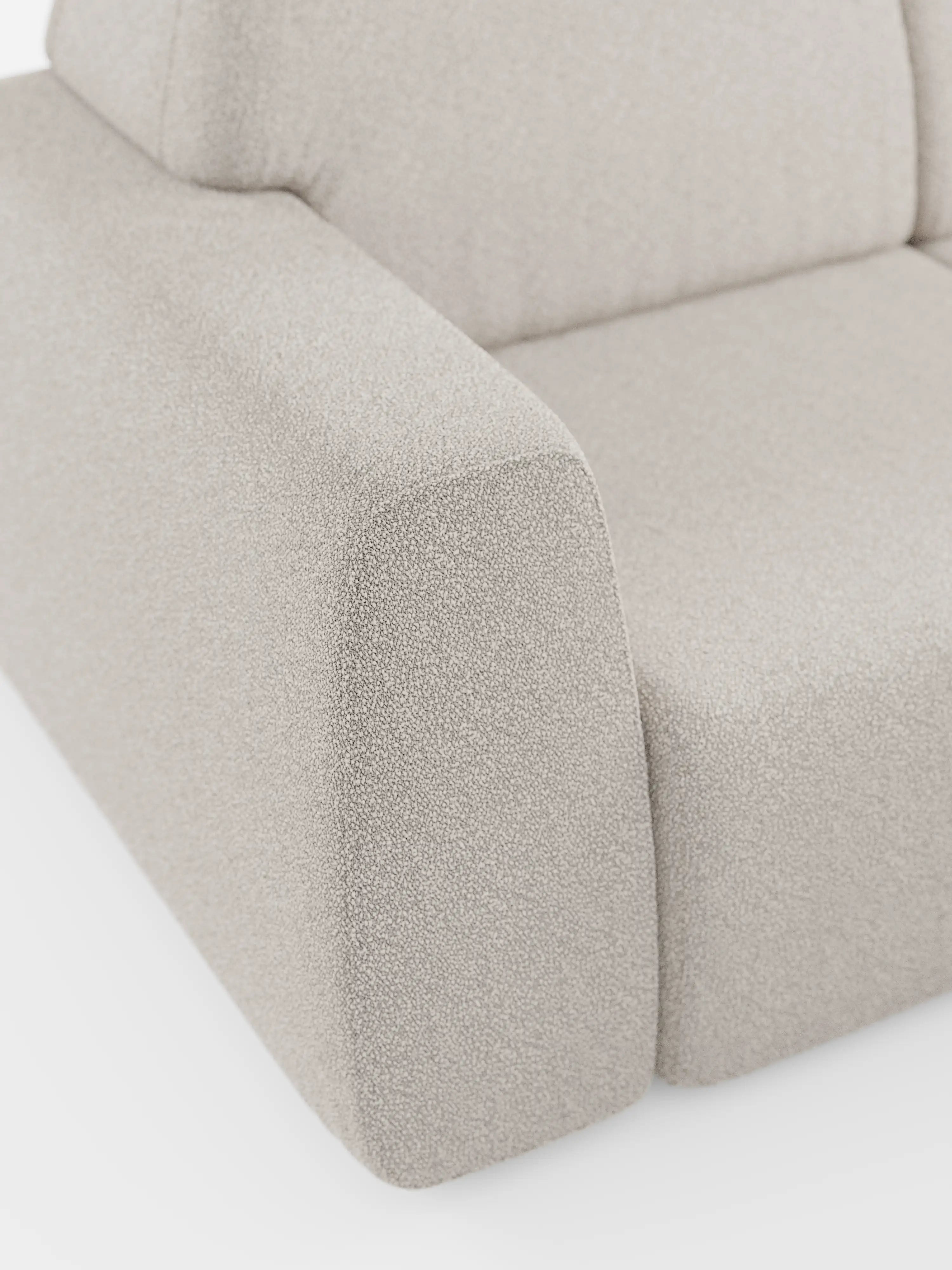 Primo piano di una poltrona in tessuto beige a trama ruvida che mostra il bracciolo sinistro, la seduta e parte dello schienale. Simile a un divano di alta gamma, il design pulito e arrotondato e la finitura morbida evocano un comfort e uno stile di prima classe sullo sfondo bianco a tinta unita. In primo piano: Orbit Divano angolare con penisola reversibile e tutte le sedute allungabili in tessuto smacchiabile effetto cotone T33 di Divani.Store.