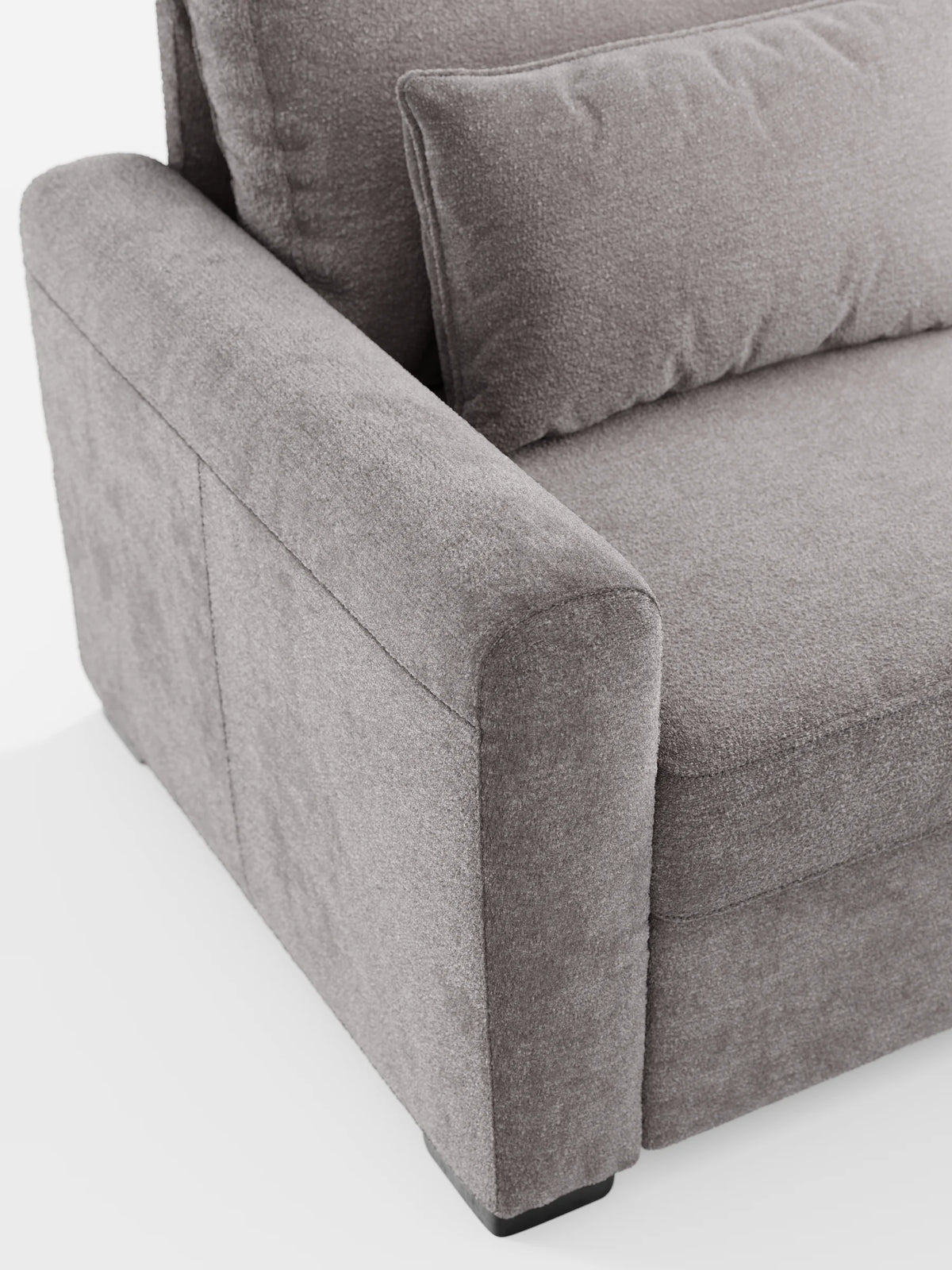 Primo piano dall'alto di un divano letto Ottaviano color taupe con letto estraibile, penisola reversibile e contenitore in tessuto materico smacchiabile, caratterizzato da un ampio bracciolo, un cuscino dello schienale rettangolare e un cuscino decorativo bianco.