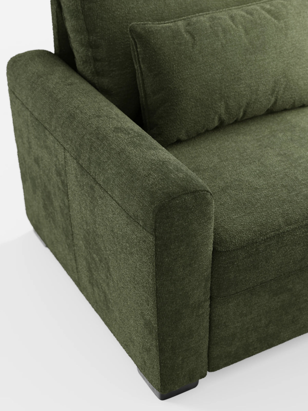 Primo piano del bracciolo e della seduta di un divano letto Ottaviano color verde oliva scuro con finitura testurizzata e letto estraibile – penisola reversibile e contenitore in tessuto materico lavabile, con un cuscino decorativo rettangolare coordinato su sfondo bianco.
