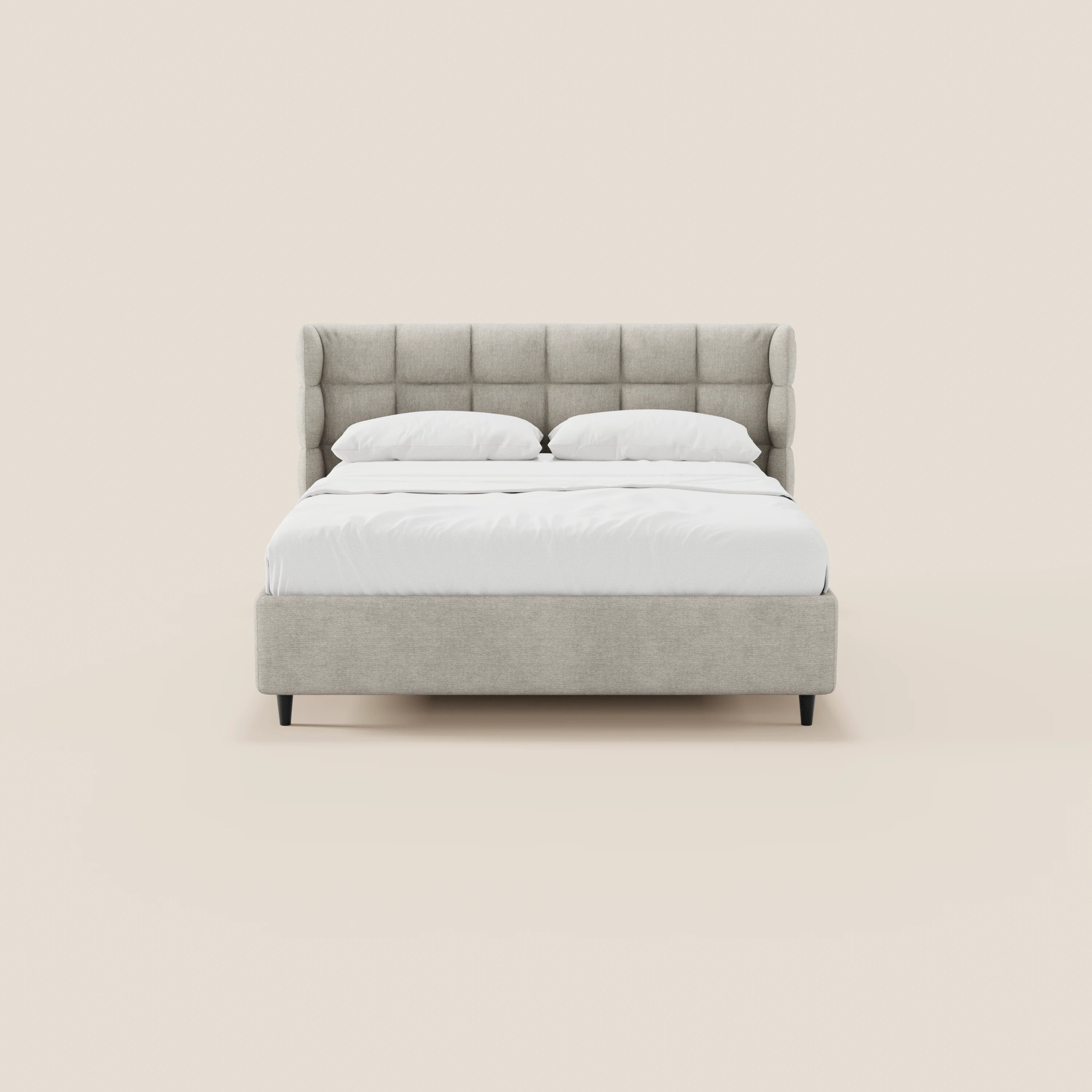 Il letto imbottito RAGNAR di Letti.store presenta una testiera capitonné avvolgente di colore grigio chiaro, gambe corte scure ed un elegante tessuto certificato Oeko-Tex®. Nella foto è raffigurato con biancheria da letto bianca e due cuscini su uno sfondo beige chiaro.