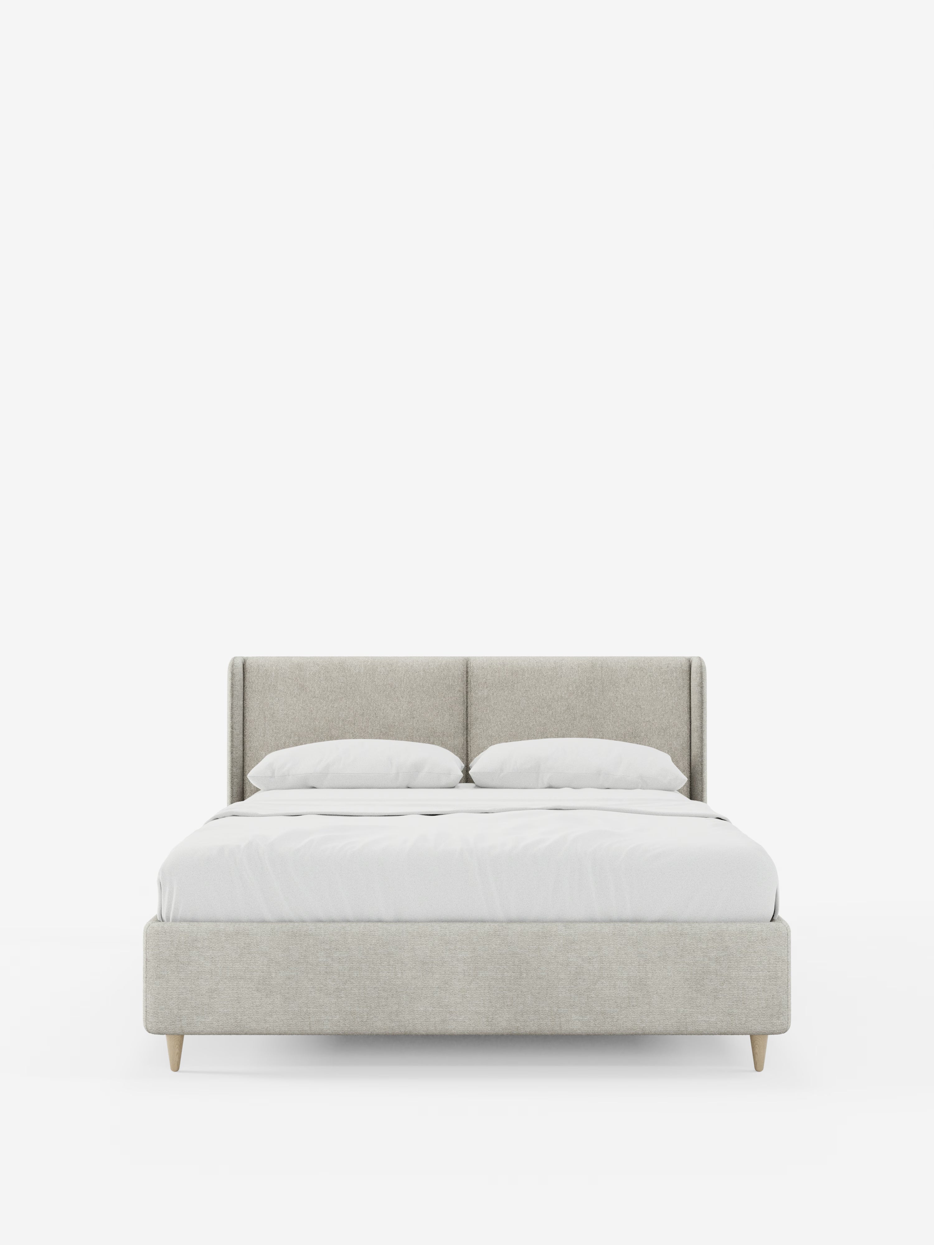 Un letto imbottito contemporaneo di colore grigio chiaro — il modello VALKIRIA, letto imbottito bicolore con contenitore di Letti.store — si caratterizza per il profilo ribassato, le gambe in legno e un’elegante testiera imbottita dal design curvo e avvolgente (testiera curva avvolgente) con cuscini di schienale. Questo elegante letto imbottito contenitore è rifatto con cura con un lenzuolo con angoli bianco, un piumone bianco e due cuscini bianchi, il tutto su uno sfondo bianco a tinta unita.