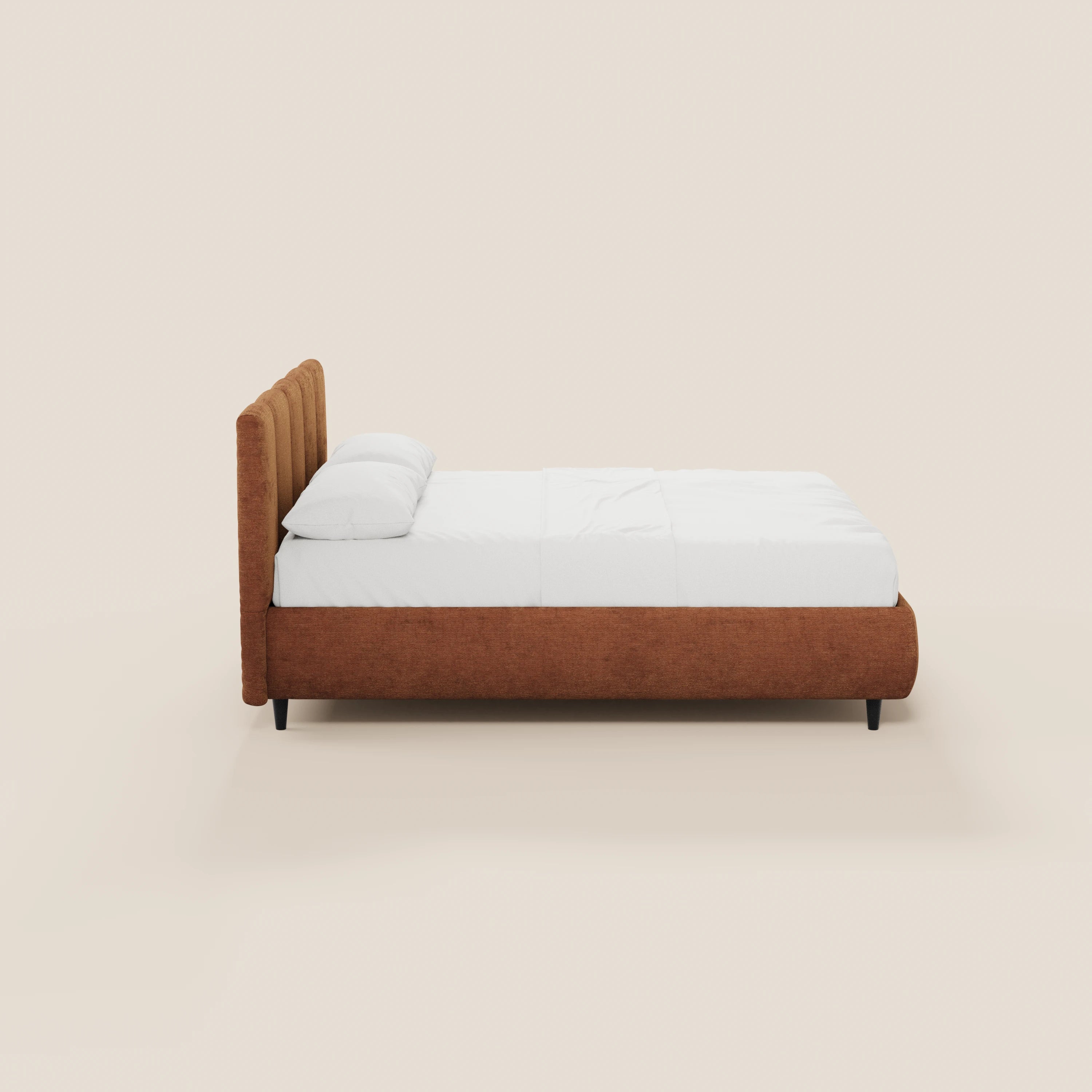 Una vista laterale del letto imbottito ARKAM di Letti.store, caratterizzato da una struttura in tessuto color ruggine certificato Oeko-Tex®, testiera con cuciture verticali, biancheria da letto e cuscini bianchi e gambe corte nere su uno sfondo beige chiaro.
