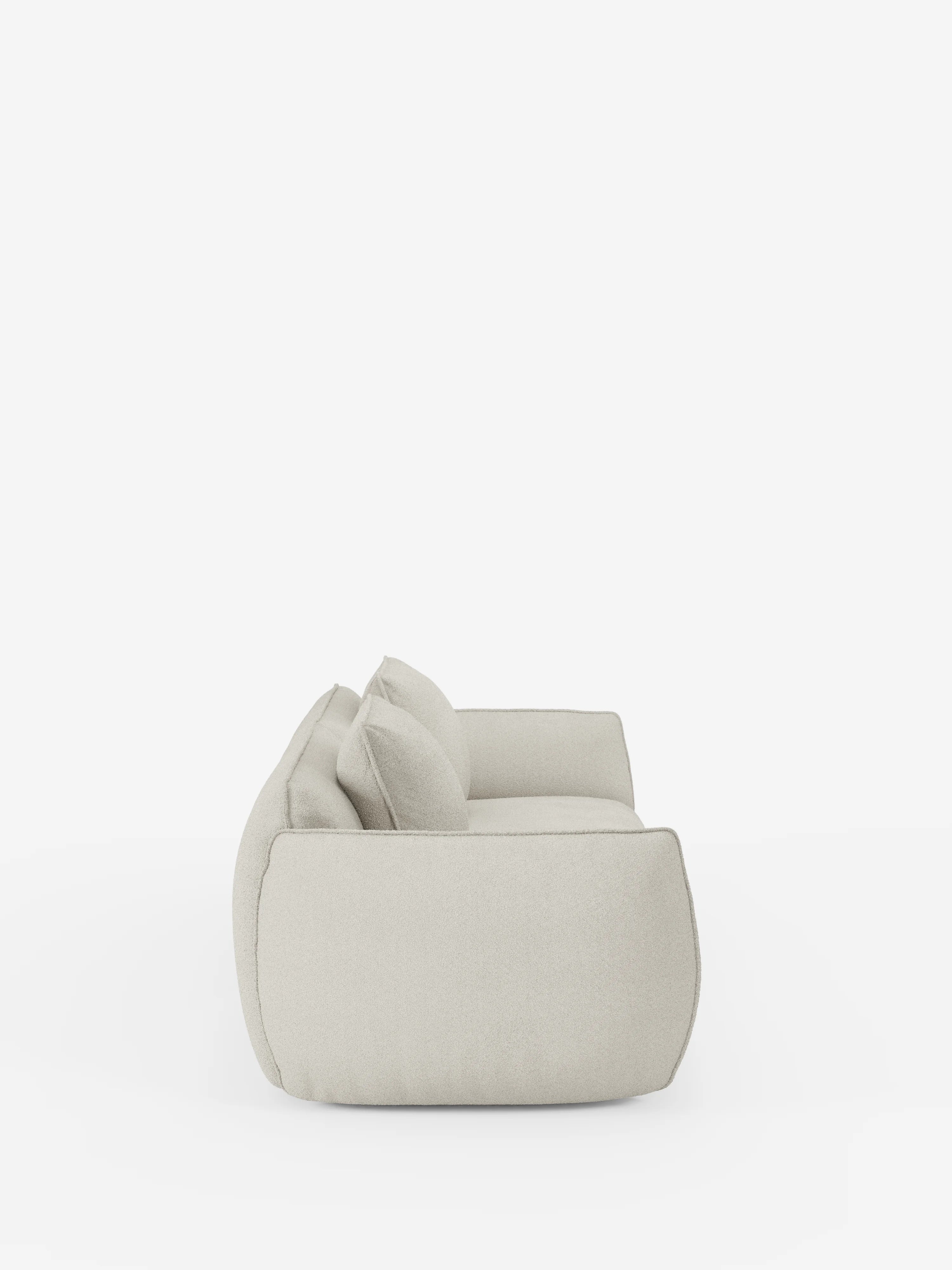 Vista laterale del divano modulare e componibile a 3 posti Nimbus da 250 cm di Divani.Store, rivestito in tessuto T33 effetto cotone, colore beige chiaro e resistente alle macchie. Questo divano modulare è dotato di due cuscini di seduta e due cuscini dello schienale, dall’aspetto morbido e soffice, e di braccioli arrotondati, il tutto raffigurato su uno sfondo bianco a tinta unita.
