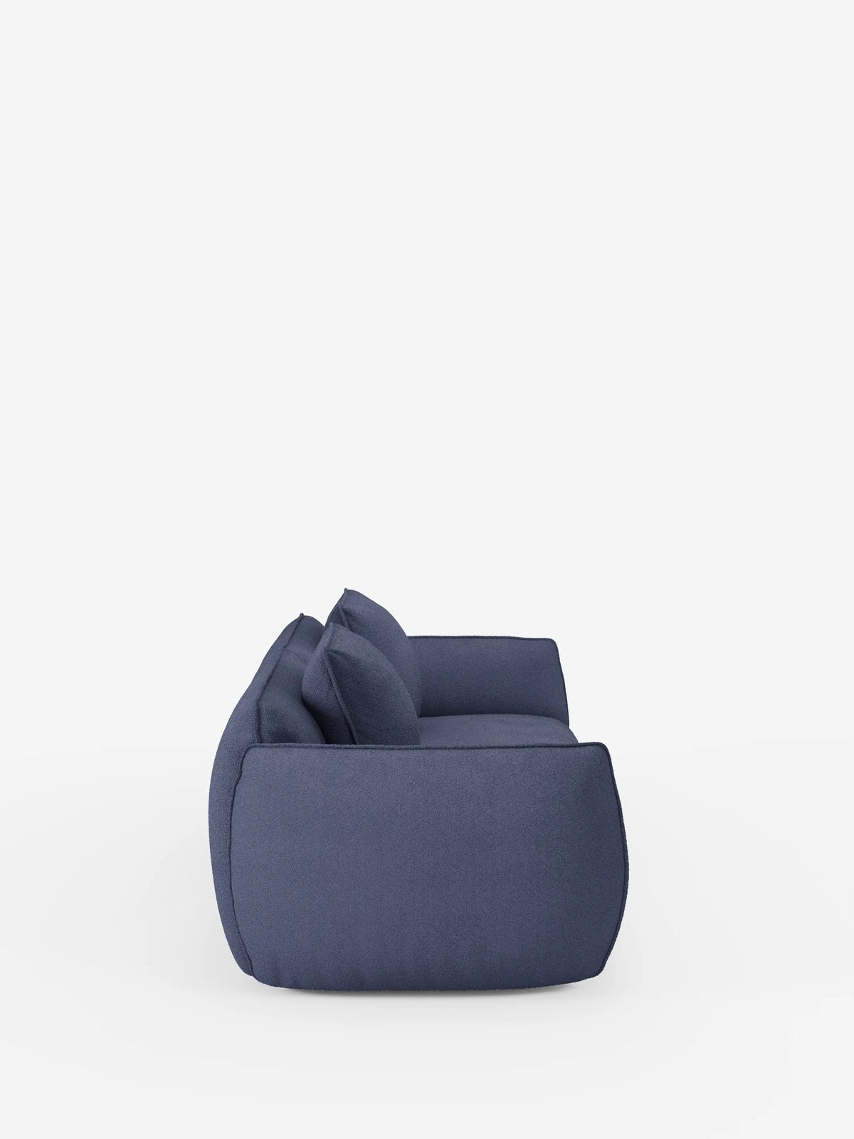 Un divano Nimbus contemporaneo a 3 posti, modulare e componibile da 250 cm di Divani.Store, in blu intenso, rivestito con tessuto t33 effetto cotone resistente alle macchie e caratterizzato da cuscini e braccioli spessi e morbidi, è raffigurato di profilo su uno sfondo bianco senza cuciture. Il design basso e squadrato del divano è impreziosito da due cuscini coordinati disposti con cura sulla superficie.