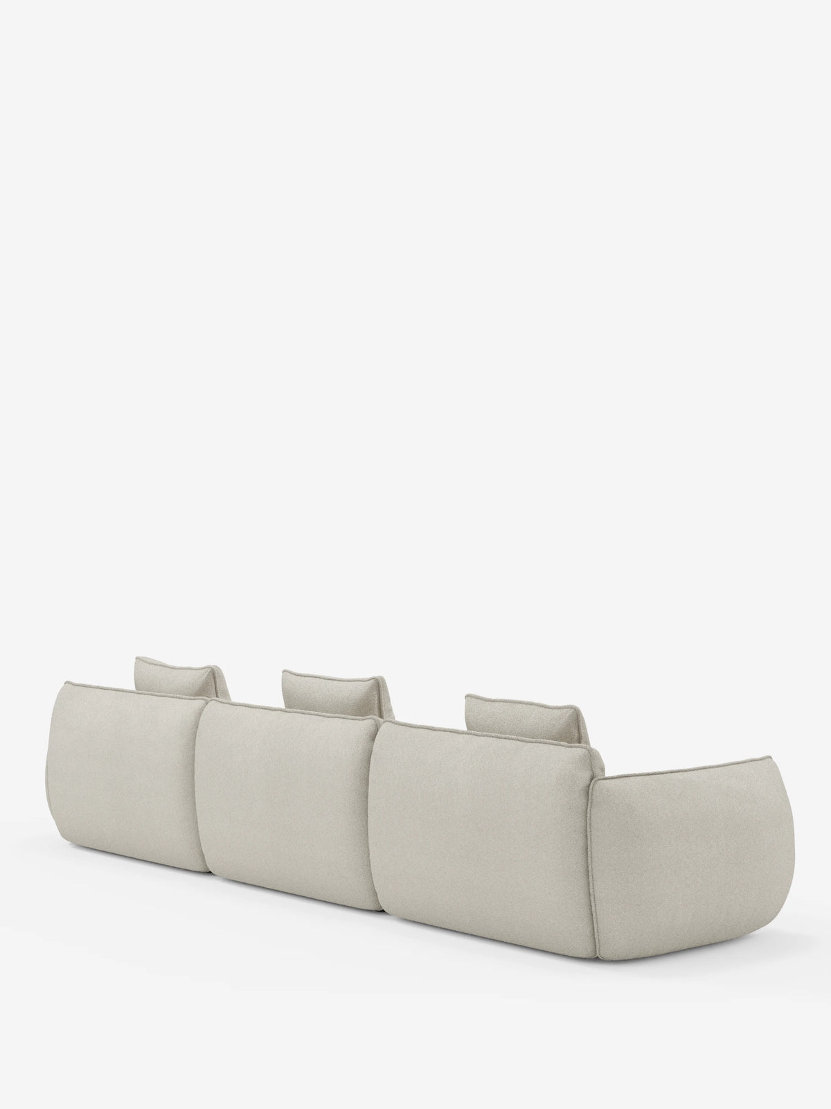 Un divano angolare contemporaneo Nimbus con penisola componibile in morbido tessuto effetto cotone smacchiabile T33 di Divani.Store, caratterizzato da tre ampie sedute senza braccioli e tre schienali bassi annessi in una tonalità beige chiaro. Visto di retro su uno sfondo bianco a tinta unita, il suo design minimalista è accentuato da bordi morbidi e arrotondati e da un aspetto soffice e imbottito che mette in risalto la moderna maestria artigianale italiana.