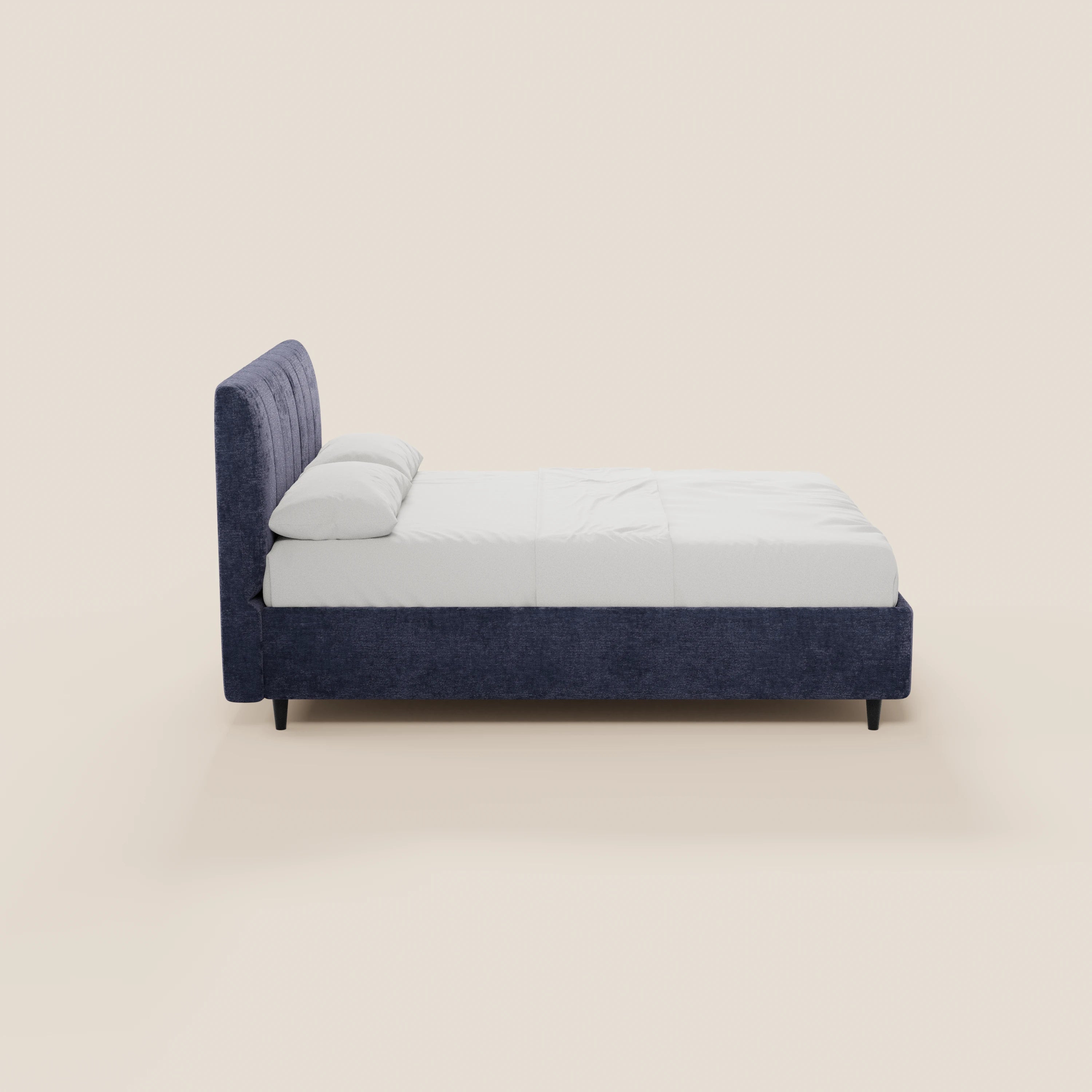 Una vista laterale del letto imbottito ONYX di Letti.store, caratterizzato da una testiera verticale blu scuro certificata Oeko-Tex®, biancheria da letto bianca con due cuscini, gambe basse nere e un elegante design contemporaneo su uno sfondo beige chiaro.