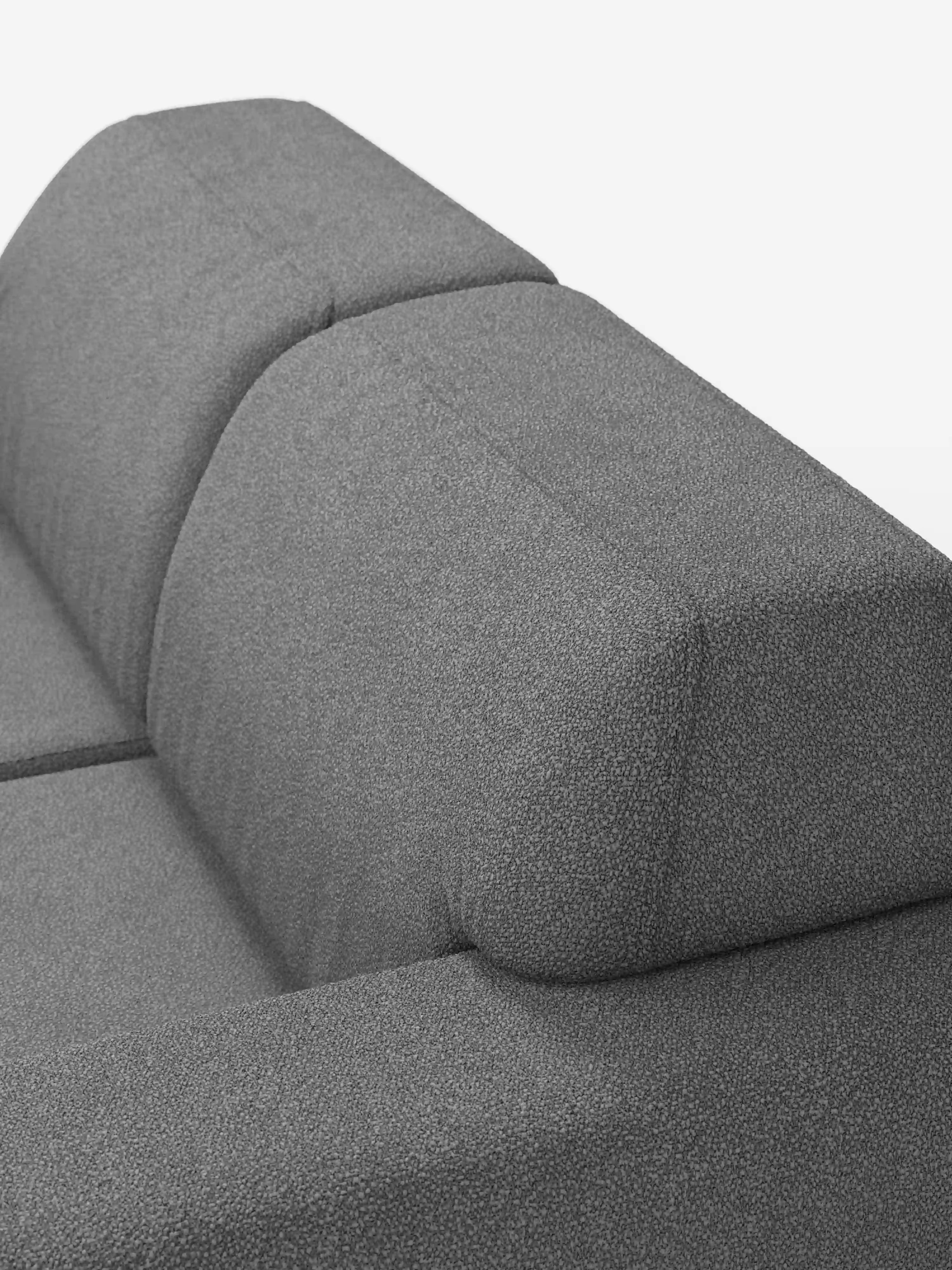 Primo piano dell'angolo superiore del divano Orbit a 2 e 3 posti con sedute scorrevoli di Divani.Store, caratterizzato da linee moderne e squadrate e da due schienali rivestiti in un tessuto grigio testurizzato con un delicato motivo maculato. Il tessuto T33 effetto cotone, completamente sfoderabile e resistente alle macchie, esalta il design contemporaneo e l’eleganza sobria di questo divano moderno, che spicca su uno sfondo bianco a tinta unita.