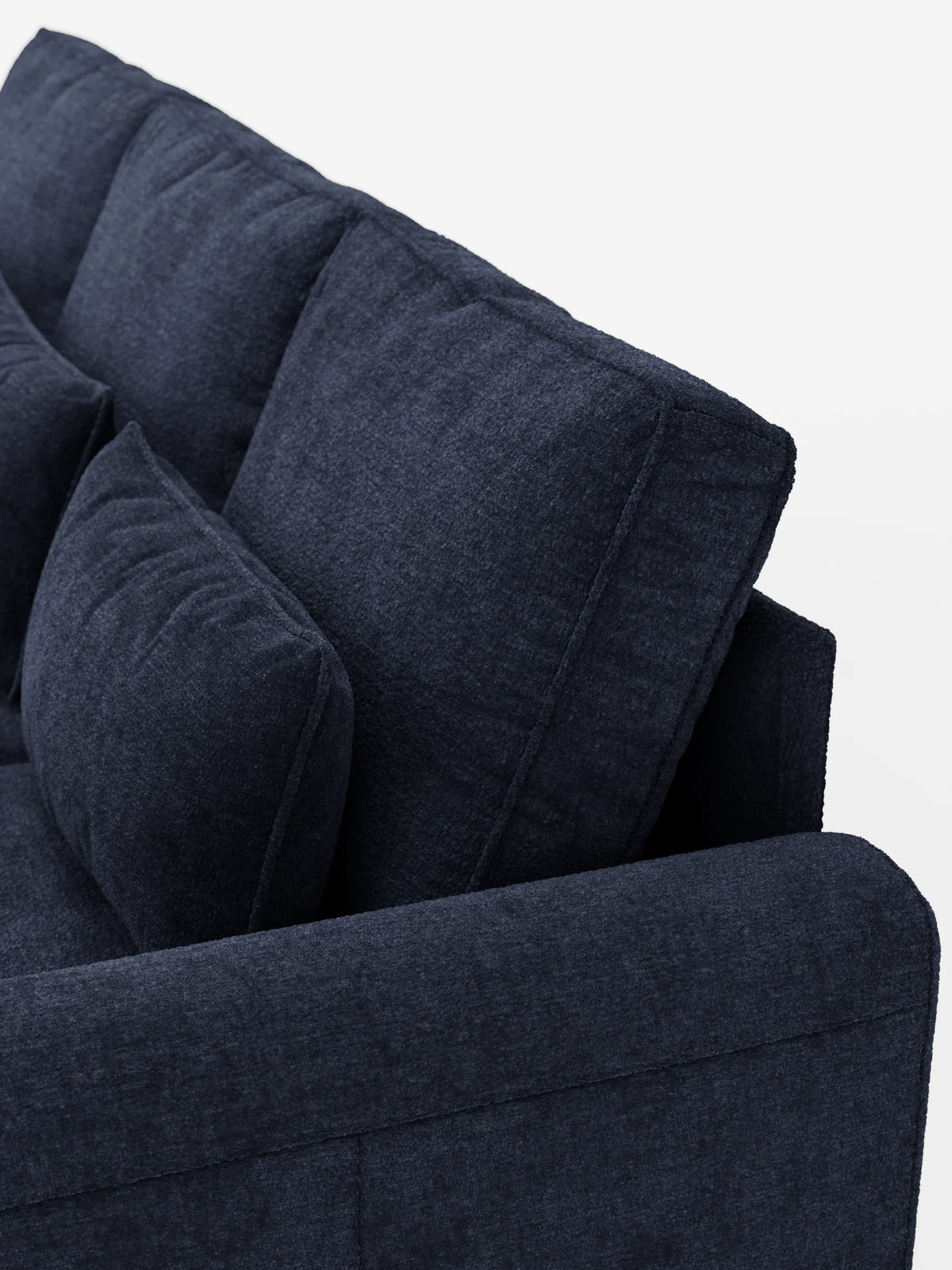 Un primo piano di un divano letto Ottaviano blu navy scuro con letto estraibile, penisola reversibile e contenitore, realizzato in tessuto materico smacchiabile, con imbottitura spessa e testurizzata, morbidi cuscini quadrati sullo schienale e un ampio bracciolo, il tutto su uno sfondo chiaro.