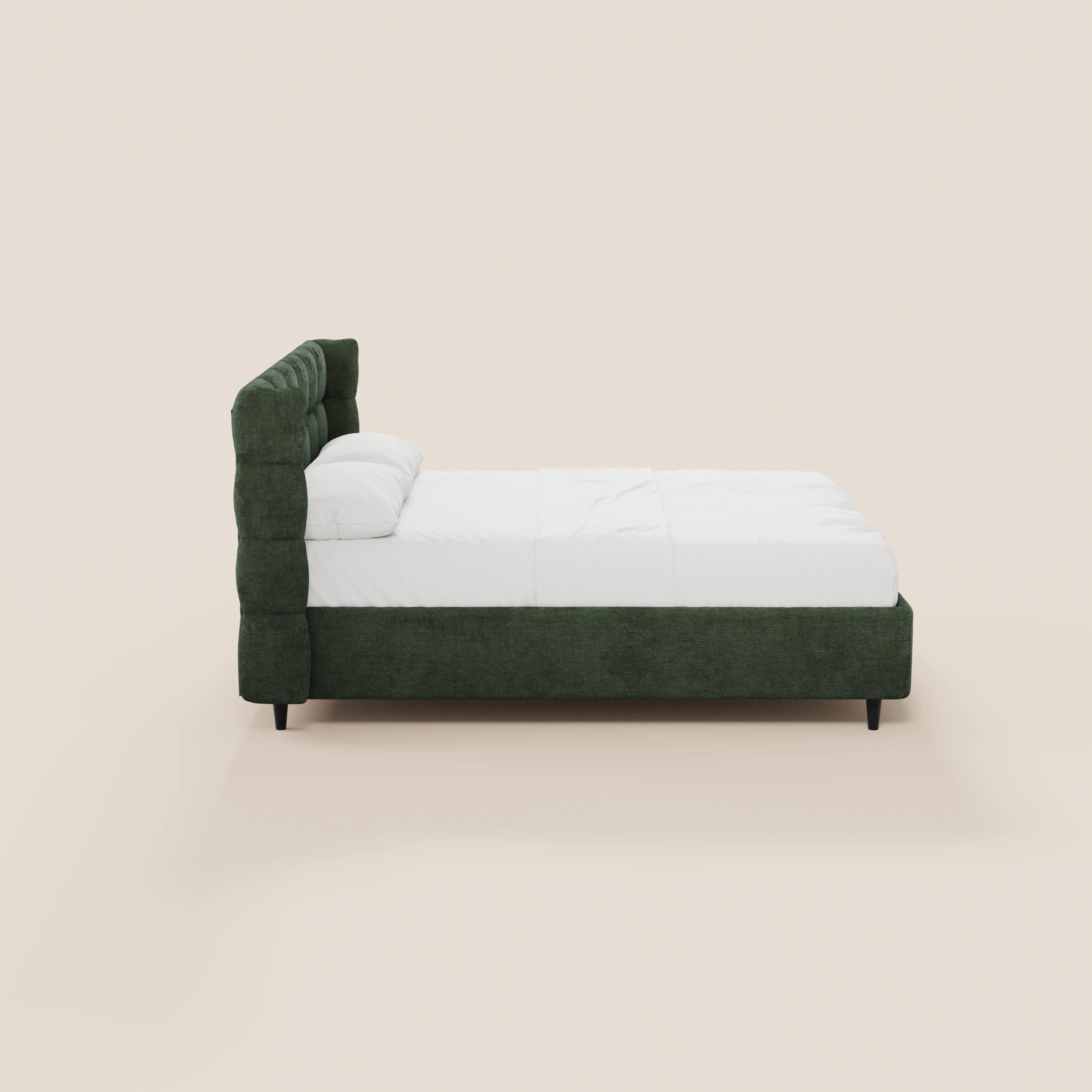 Vista laterale del letto imbottito RAGNAR di Letti.store, caratterizzato da una struttura in tessuto verde scuro certificato Oeko-Tex® con una testiera avvolgente capitonné, rifinito con cura con biancheria da letto bianca e due cuscini, su uno sfondo beige chiaro a tinta unita.
