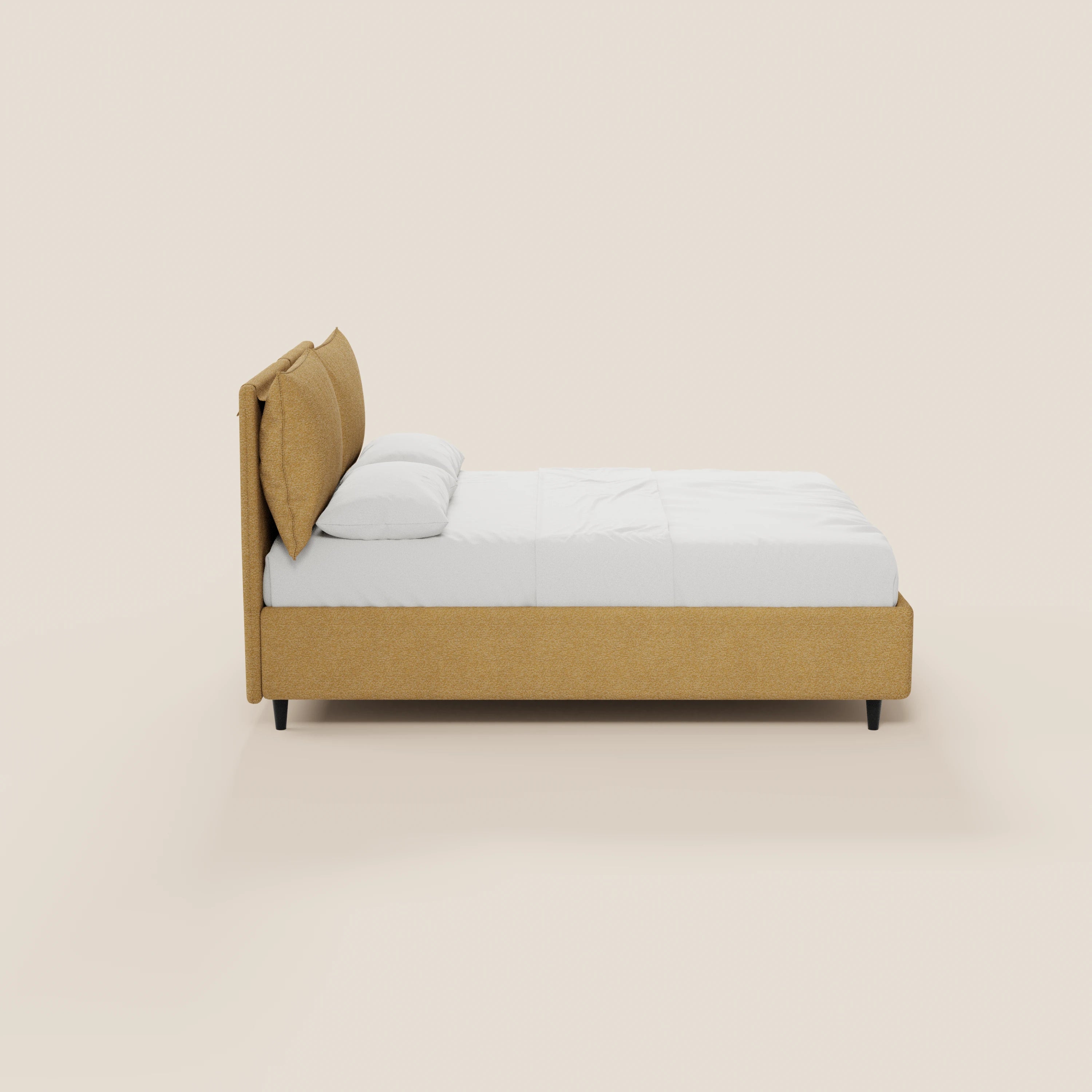 Vista laterale del letto imbottito ZAYRON di Letti.store, caratterizzato da una struttura in tessuto giallo senape certificato Oeko-Tex®, cuscini morbidi regolabili, vano contenitore e un materasso bianco, il tutto su uno sfondo beige chiaro a tinta unita.
