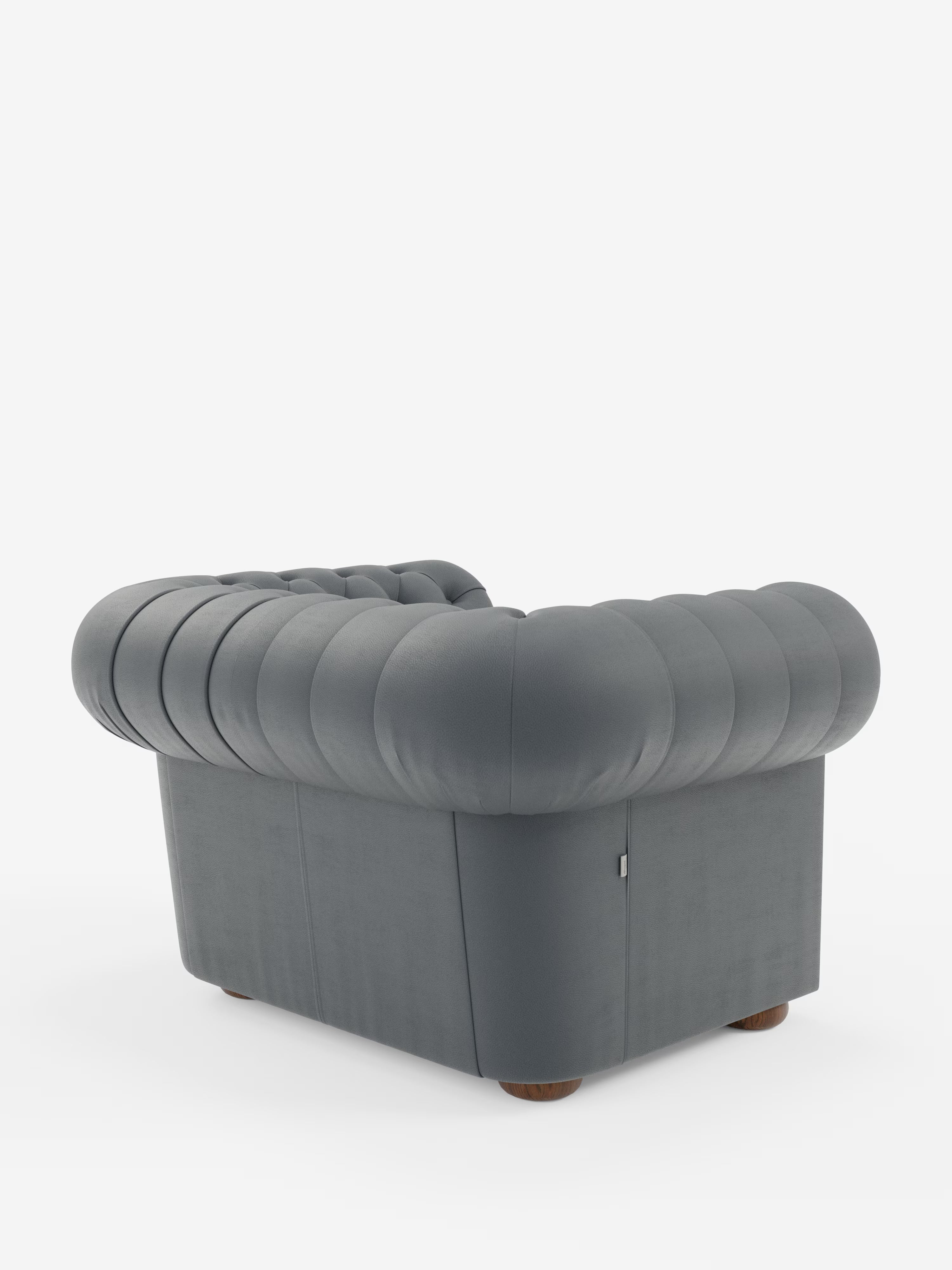 La poltrona Chester in vera pelle spessorata con capitonné artigianale di Divani.Store è una moderna poltrona grigia caratterizzata da un morbido rivestimento arrotondato e trapuntato e da uno schienale basso che richiama l’eleganza classica di una poltrona capitonné. Sostenuta da piccole gambe rotonde in legno, la poltrona è fotografata su uno sfondo bianco a tinta unita, con un’angolazione che ne mette in risalto l’angolo e il profilo laterale.