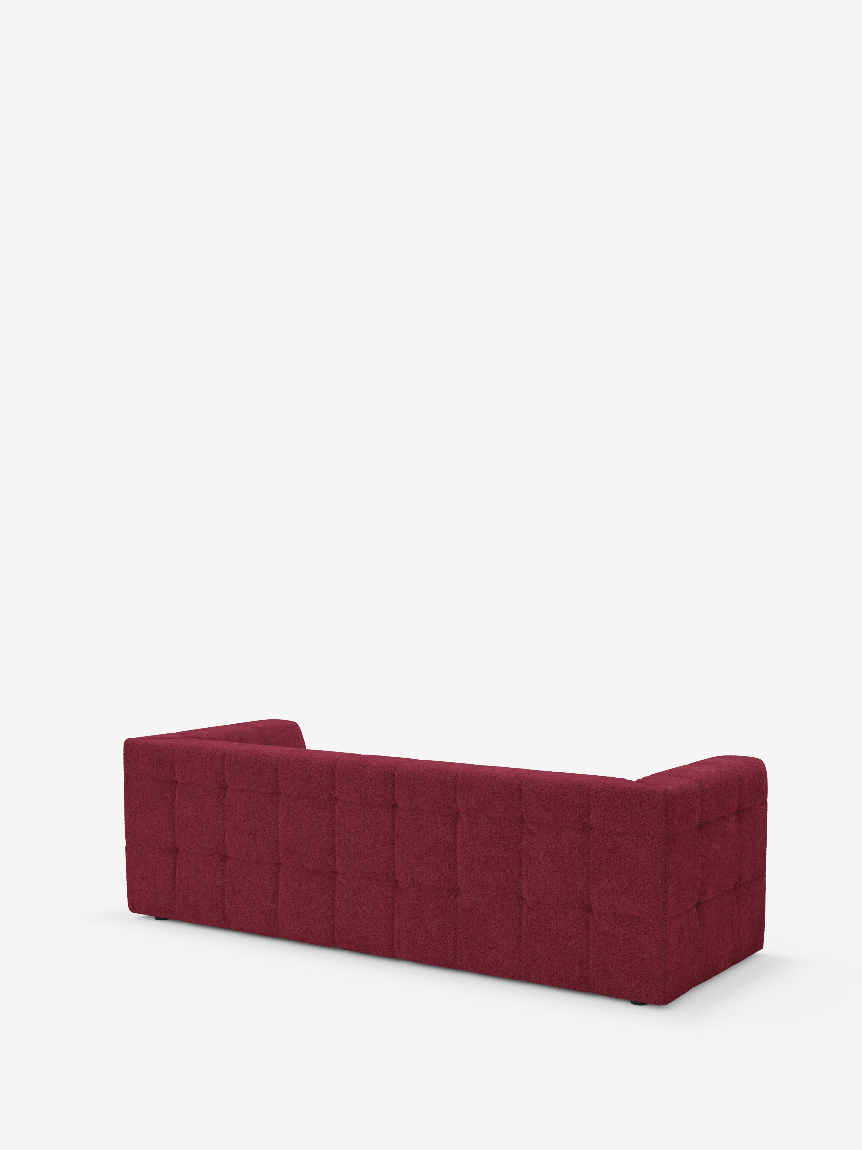 Un divano modulare Mosaic Divano a 3 e 4 posti dal design contemporaneo e dal profilo basso, firmato Divani.Store, rivestito in tessuto bouclé T21 rosso intenso antimacchia con motivo quadrato capitonné. Il divano è raffigurato di retro, a sottolineare la sua forma rettangolare e le linee pulite su uno sfondo bianco a tinta unita.
