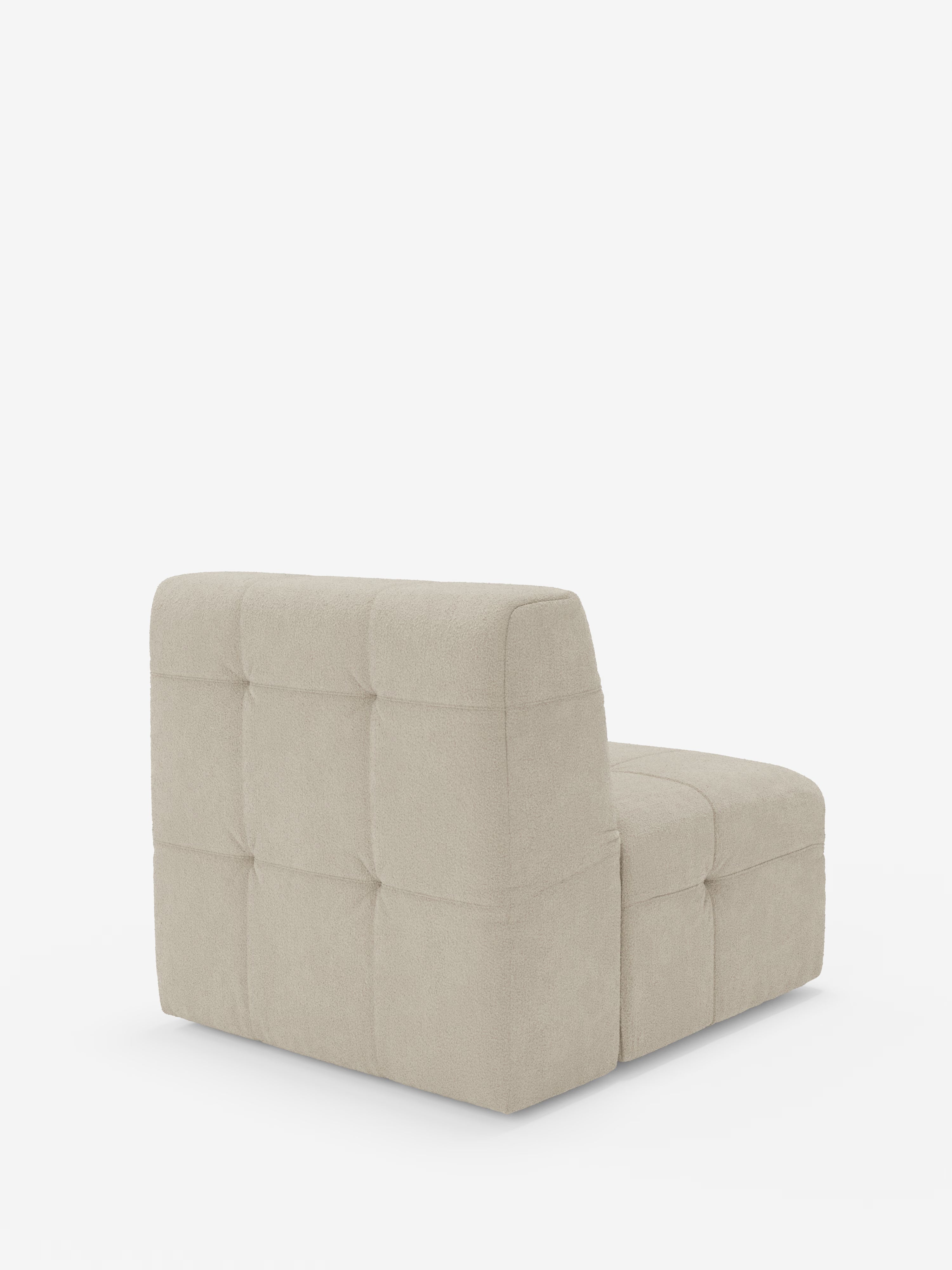 Una moderna poltrona Mosaic Modulo da 77 cm, senza braccioli e di colore beige, firmata Divani.Store, spicca su uno sfondo bianco a tinta unita, caratterizzata da un morbido rivestimento capitonné in tessuto bouclé T21 resistente alle macchie. Il modello presenta uno schienale e una seduta bassi e squadrati, con imbottitura morbida e cuciture a griglia, per un design minimalista e accogliente.