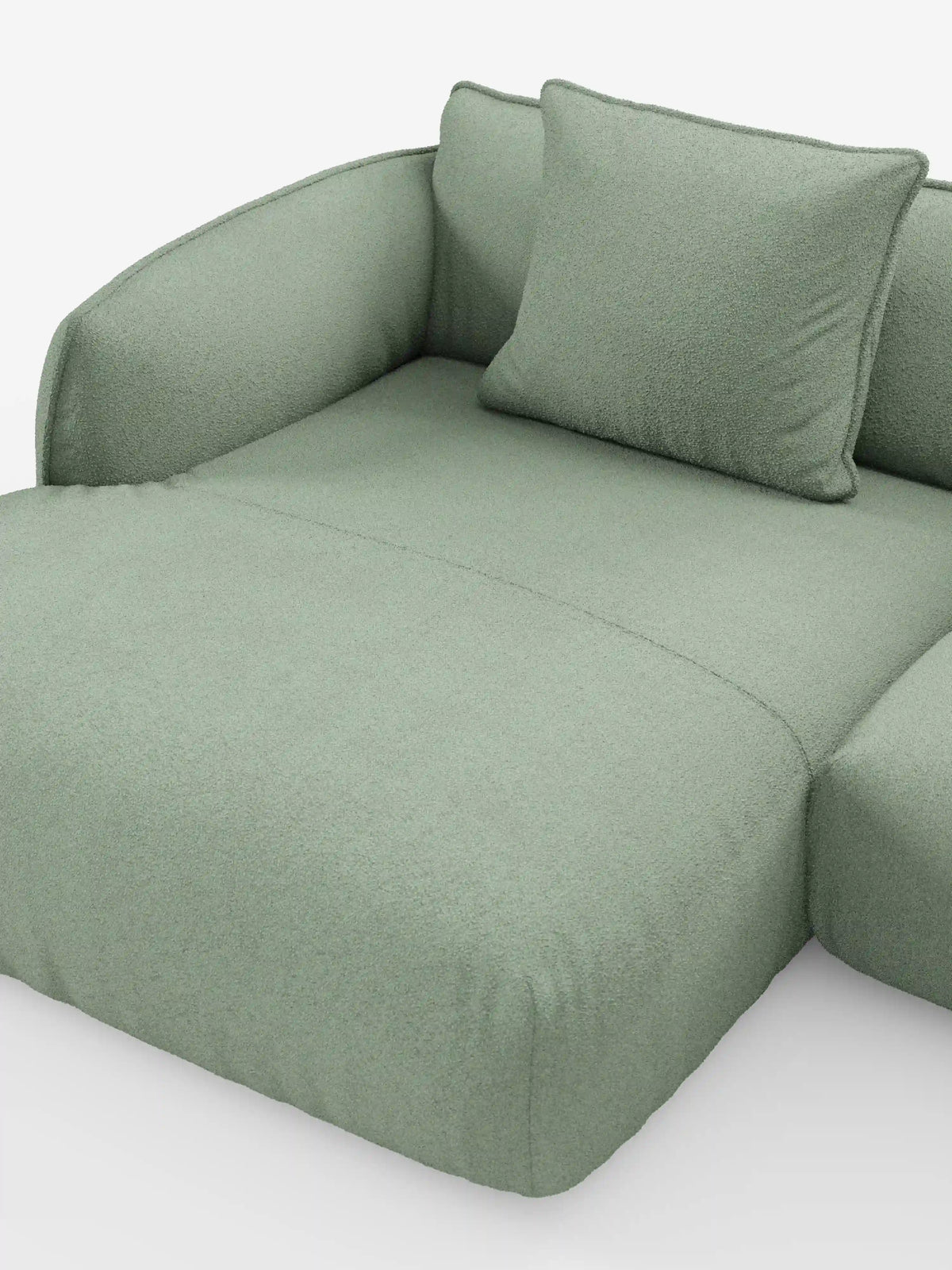 Un primo piano del divano angolare panoramico componibile Nimbus con penisola e angolo in tessuto smacchiabile T33 di Divani.Store, caratterizzato da un design moderno in verde chiaro con braccioli elegantemente ricurvi e un cuscino coordinato. Il rivestimento morbido e dalla trama particolare evoca l'eccellenza artigianale del Made in Italy, mentre lo sfondo bianco a tinta unita accentua l'estetica minimalista e confortevole di questo elemento d'arredo componibile.